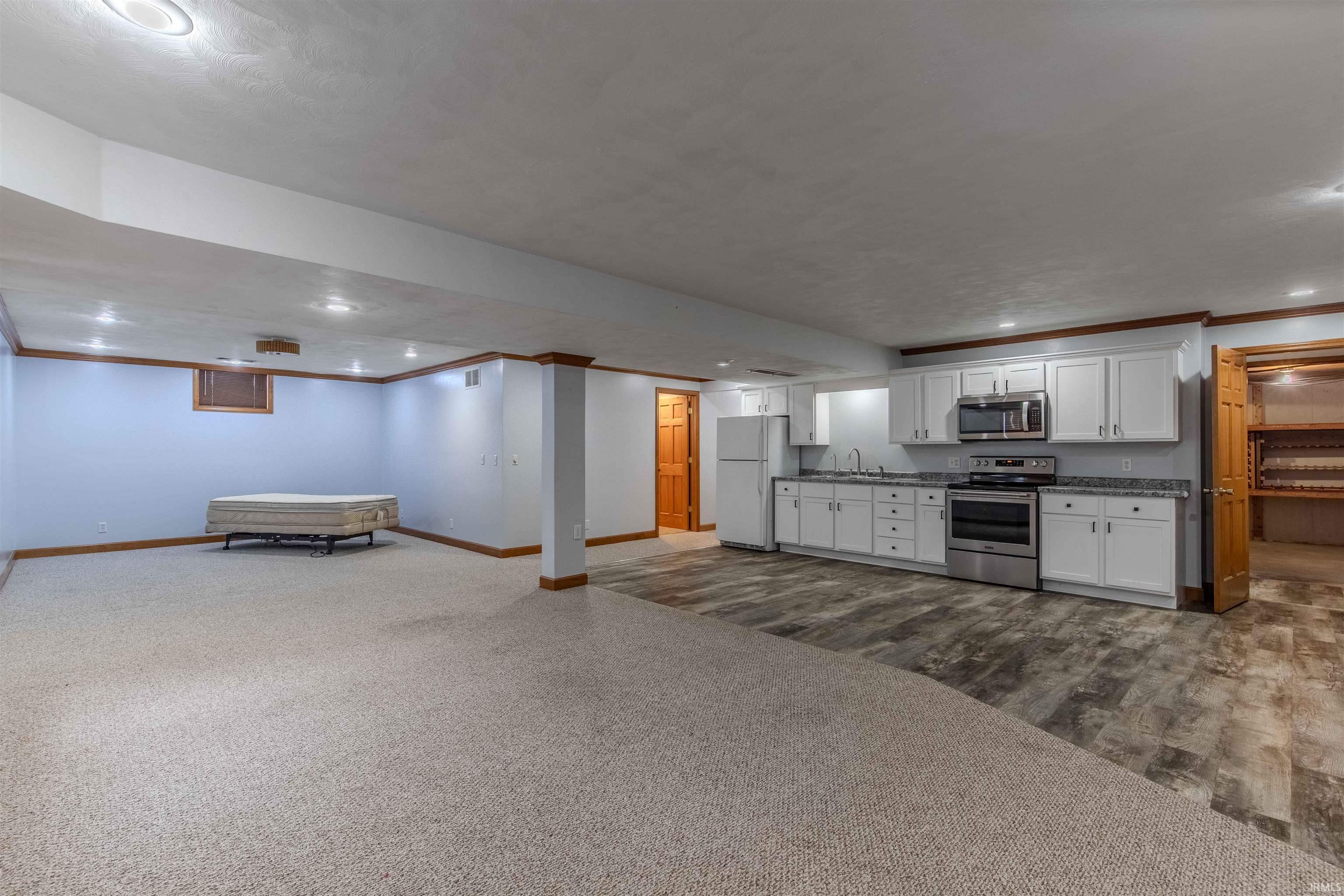 Kitchen featuring open floor plan, recessed lighting, white cabinetry, appliances with stainless steel finishes, and dark carpet