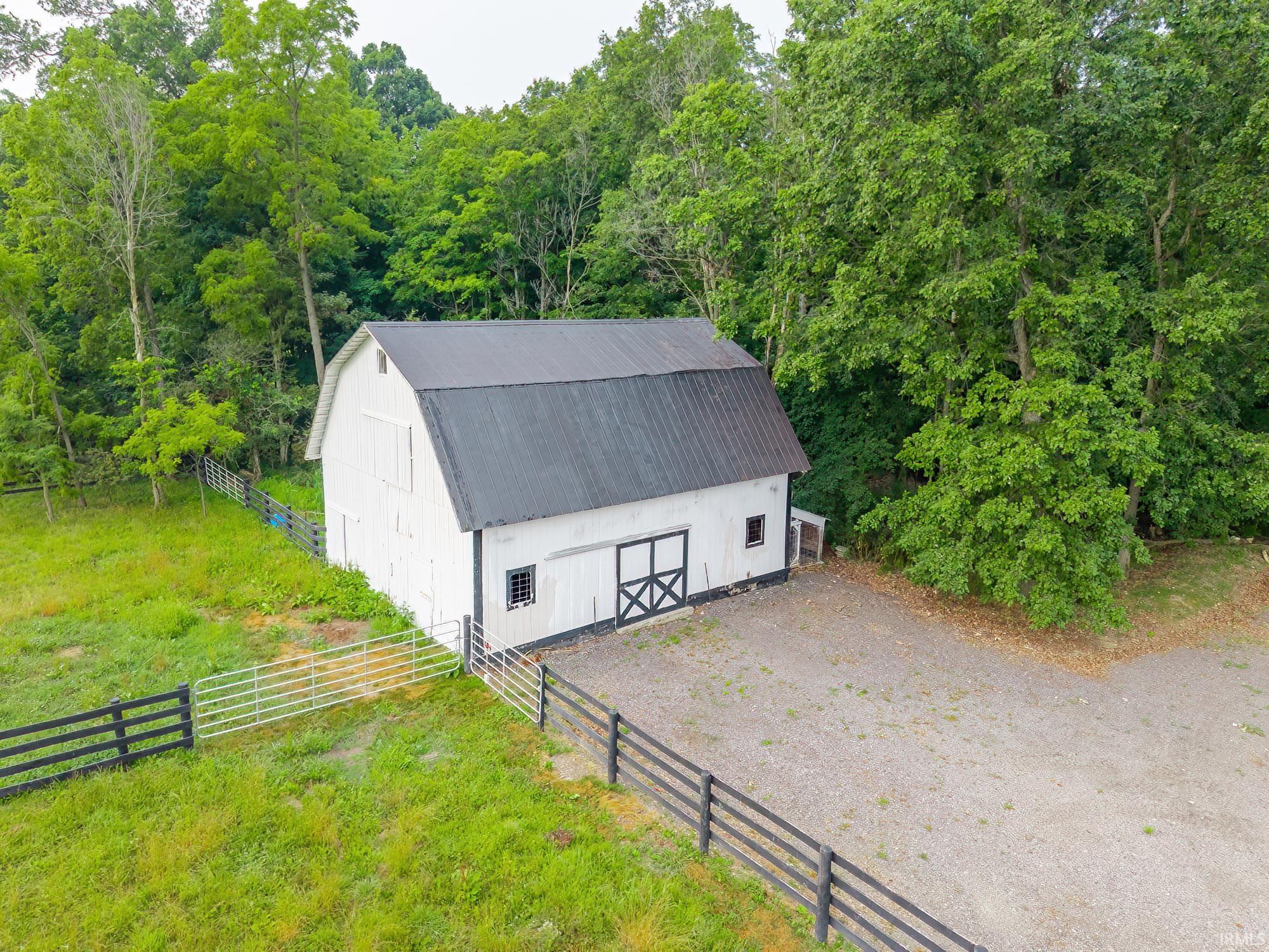 White barn structure featuring a black metal roof and black trim