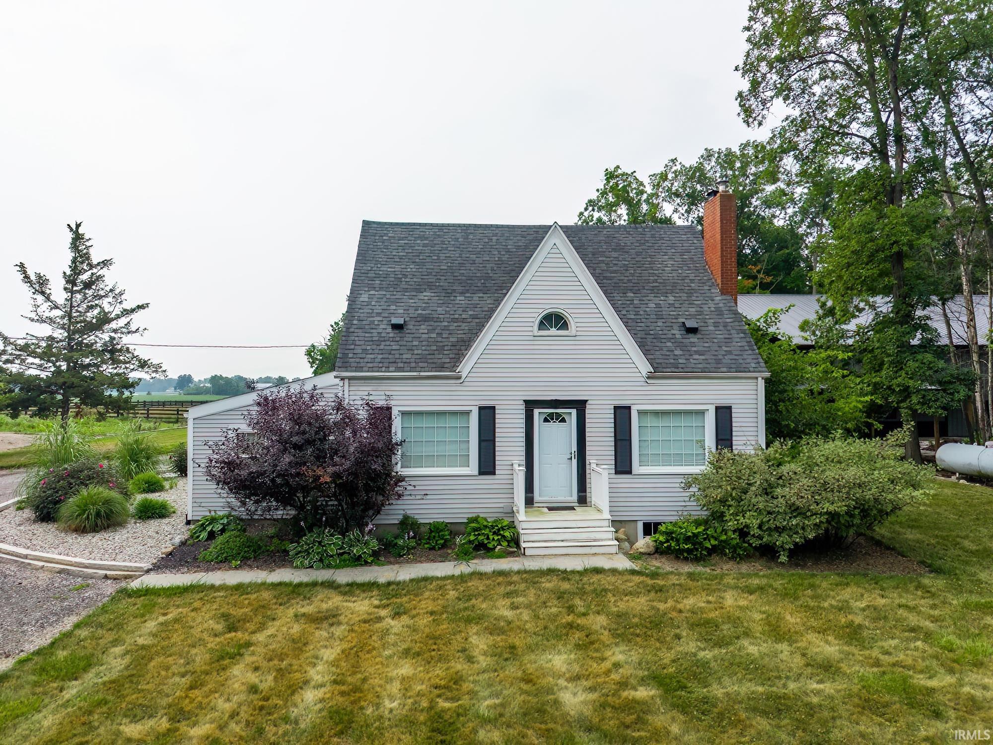 Charming home with light-colored siding and a dark shingled roof