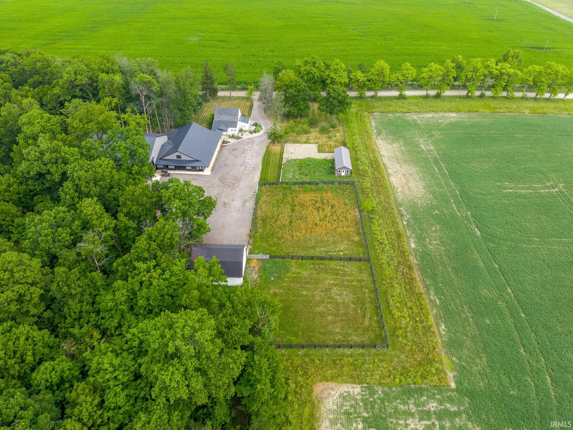 Aerial perspective showcasing a modern-style residence with a dark roofline, surrounded by dense mature trees