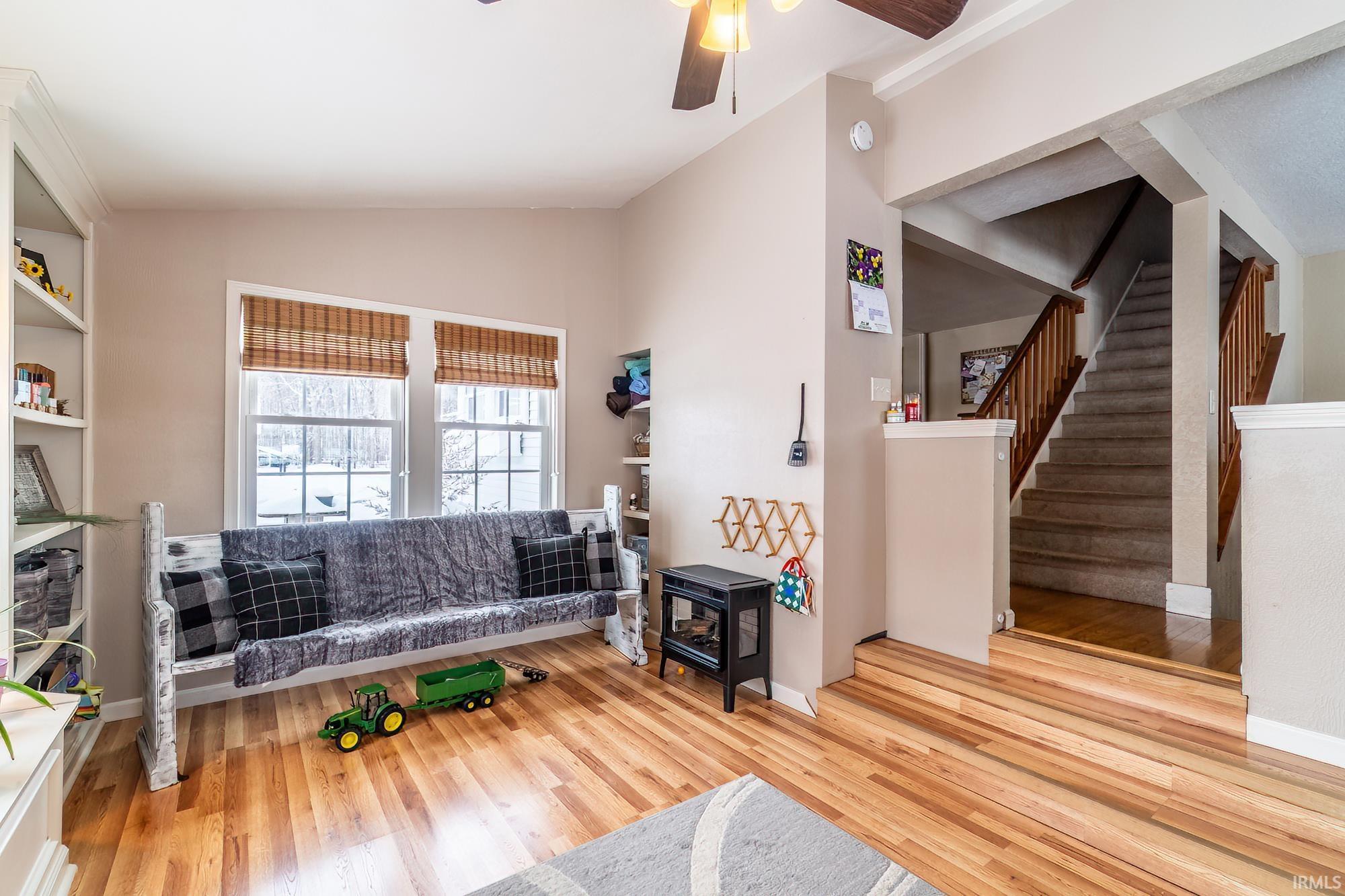 Sitting room featuring a ceiling fan, lofted ceiling, stairway, and wood finished floors