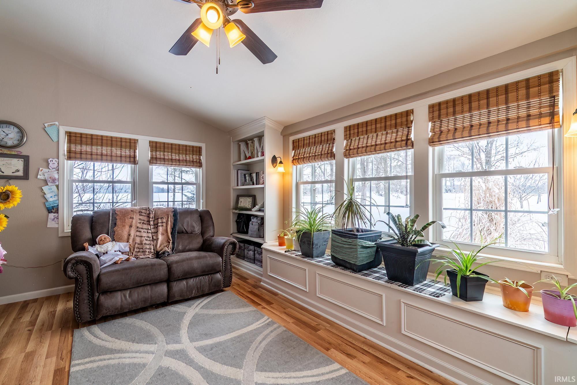 Living area featuring lofted ceiling, light wood-style flooring, and a ceiling fan