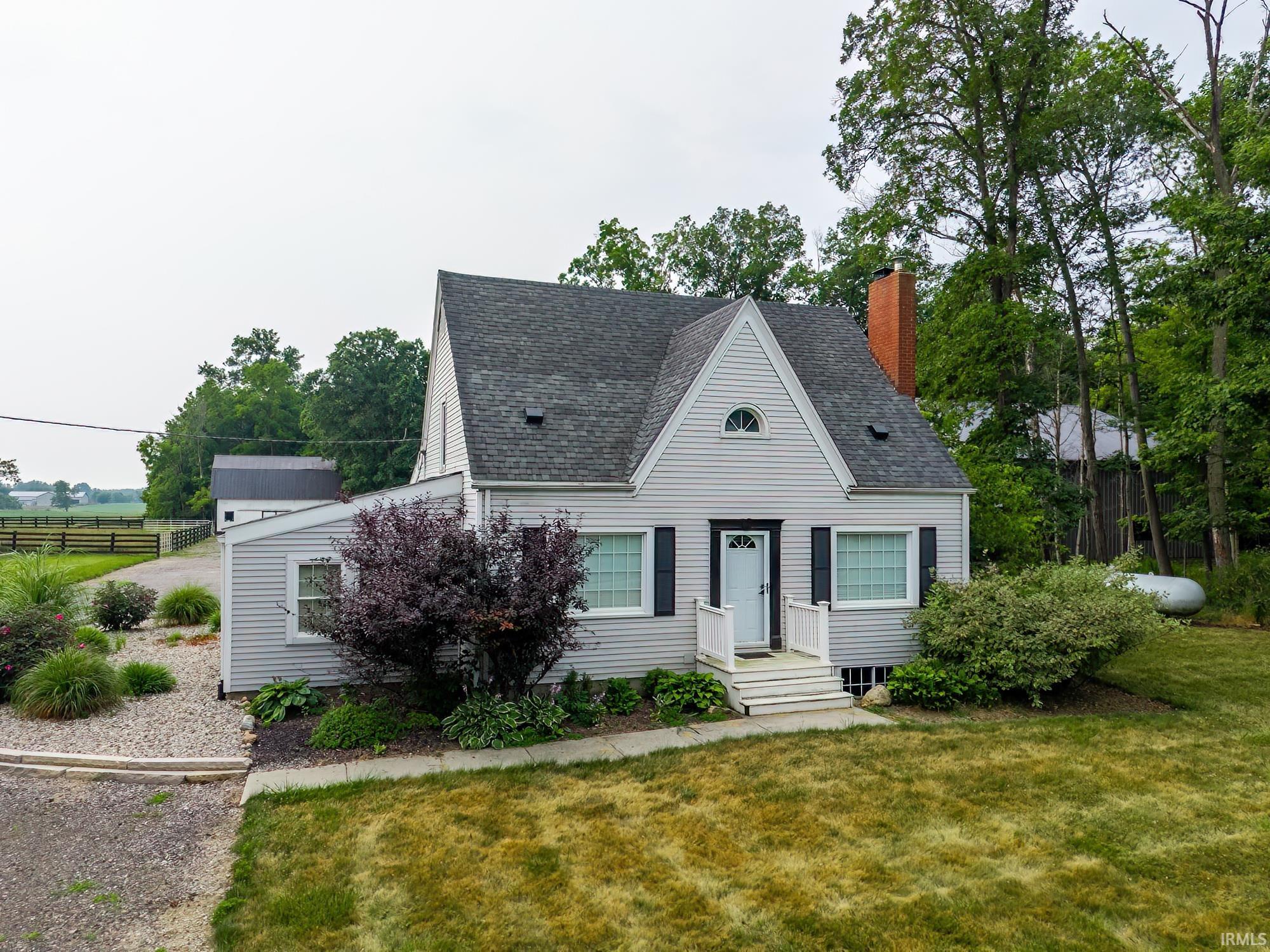 Gable-front home featuring light gray siding and dark shutters