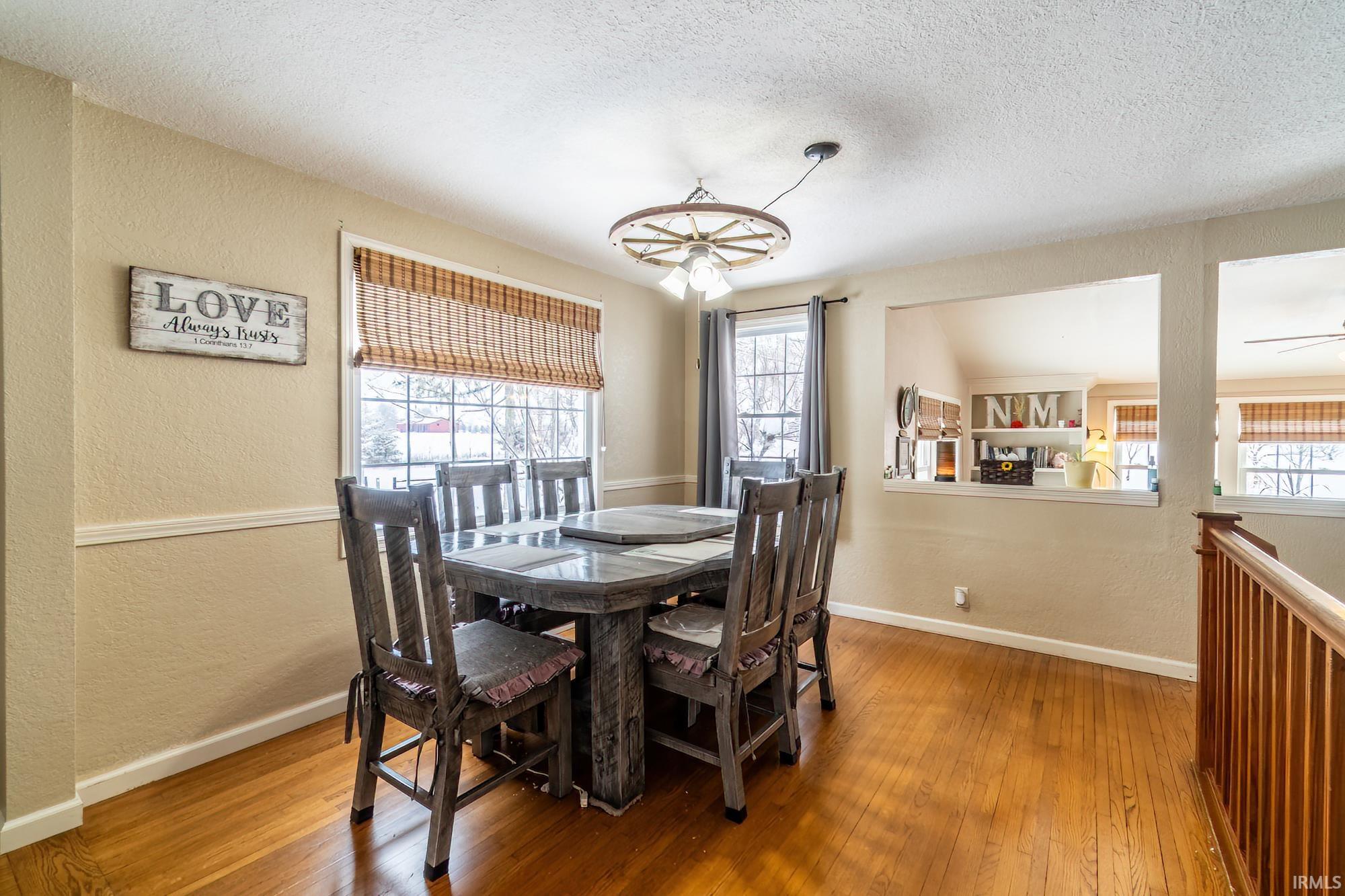 Dining room with a textured wall, hardwood / wood-style flooring, a textured ceiling, healthy amount of natural light, and a chandelier