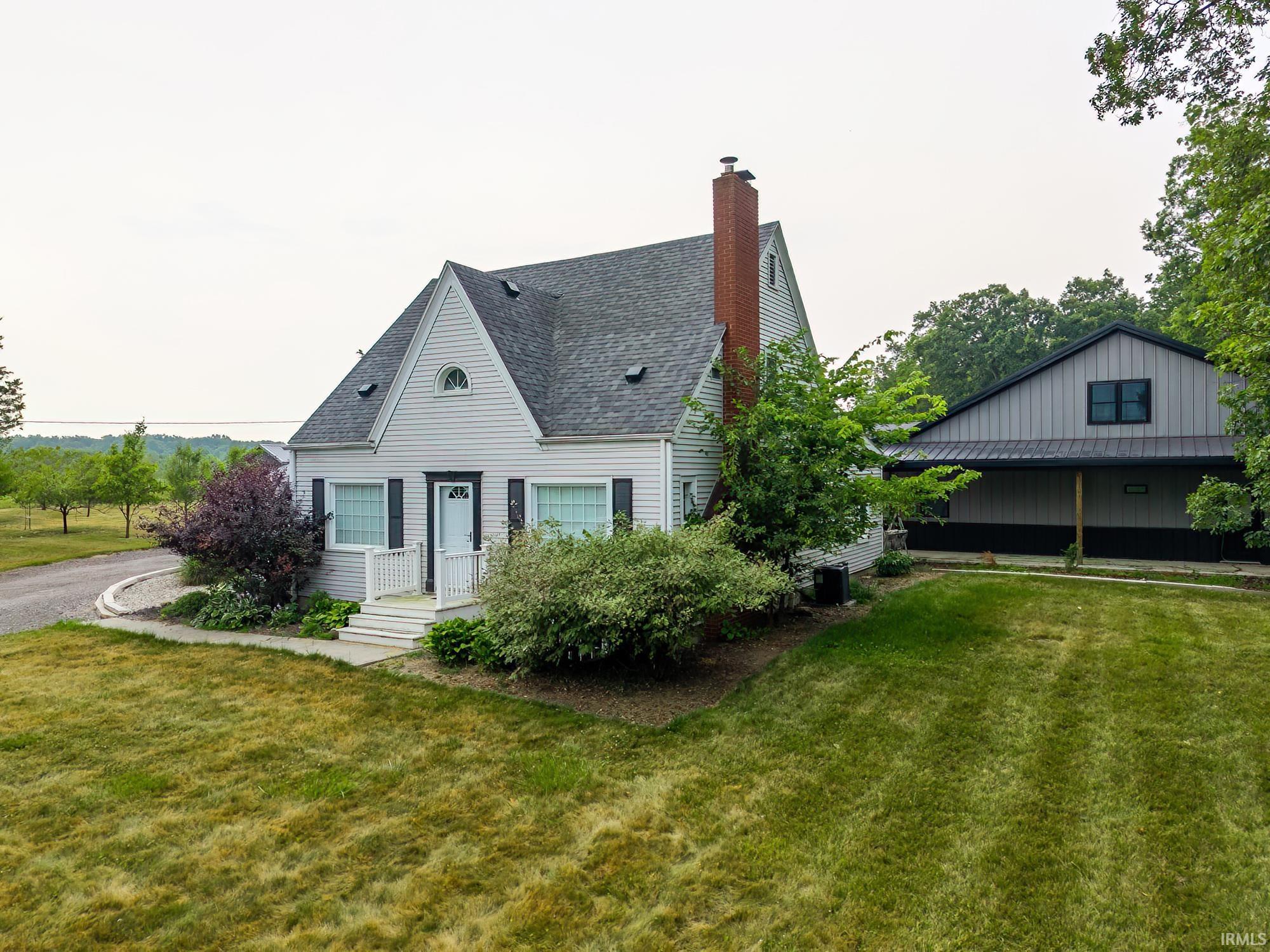 Traditional residence featuring light siding, dark shutters, and a prominent brick chimney