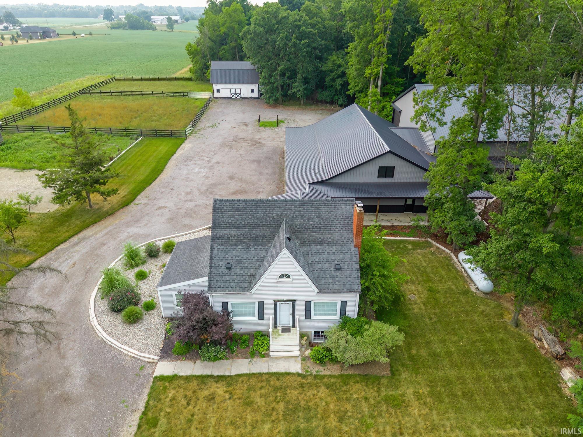 Gable-front home featuring a gray exterior, dark shingle roof, and white trim accents