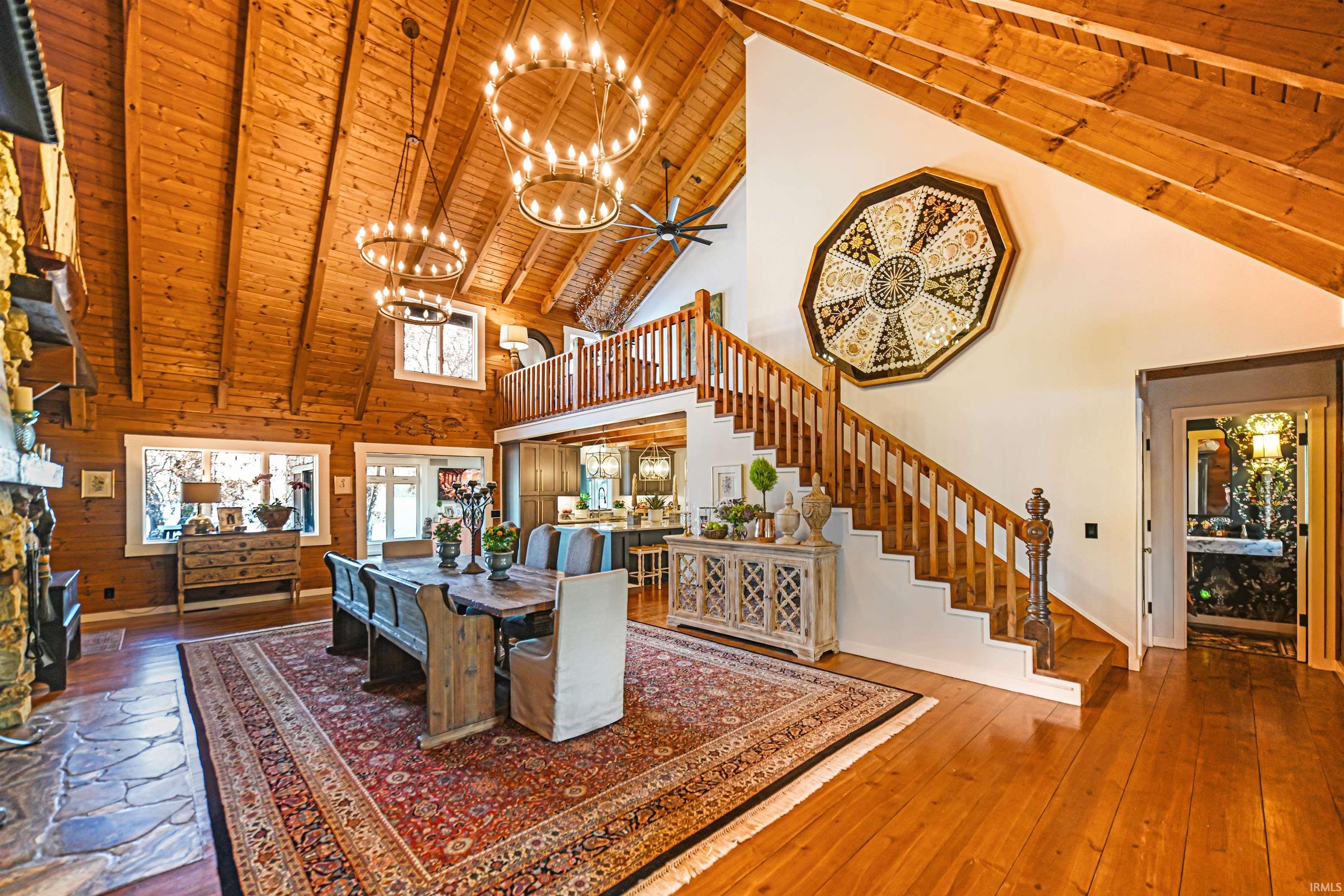 Living room featuring a wood ceiling with exposed beams, high vaulted ceiling, stairway, wooden walls, and a chandelier