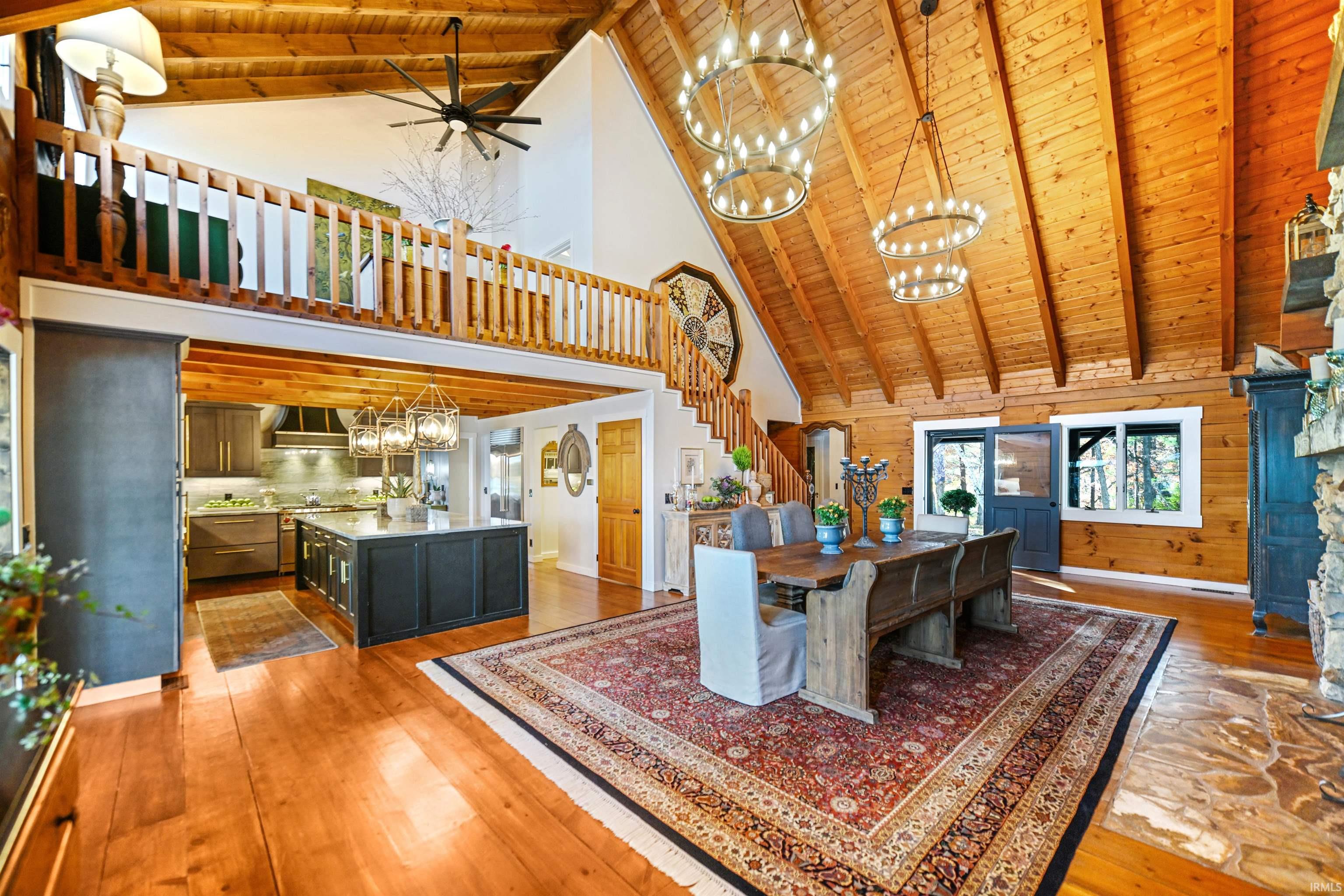 Dining space featuring a wooden ceiling with exposed beams, high vaulted ceiling, stairway, light wood finished floors, and a chandelier