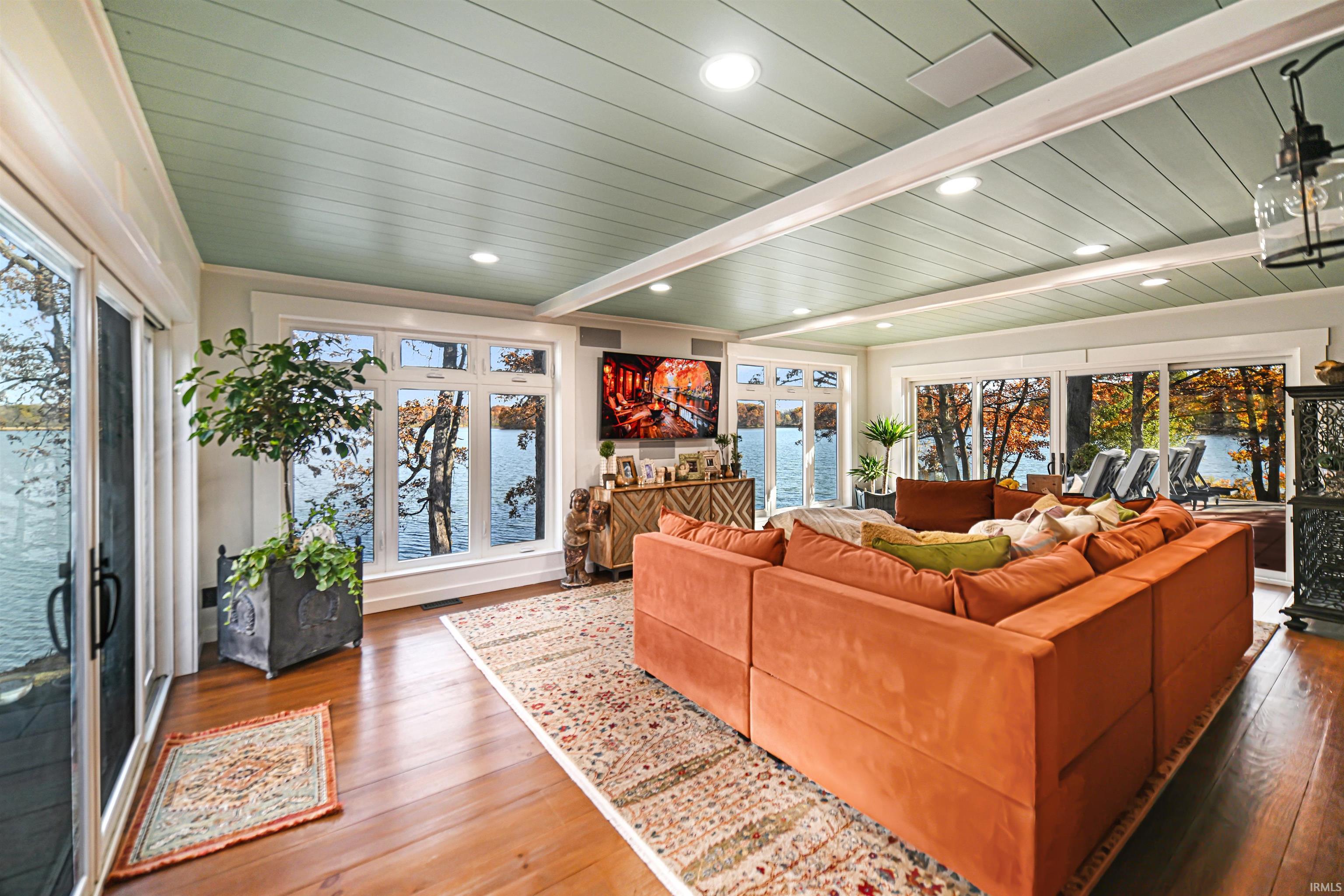 Sunroom / solarium with a water view and beam ceiling