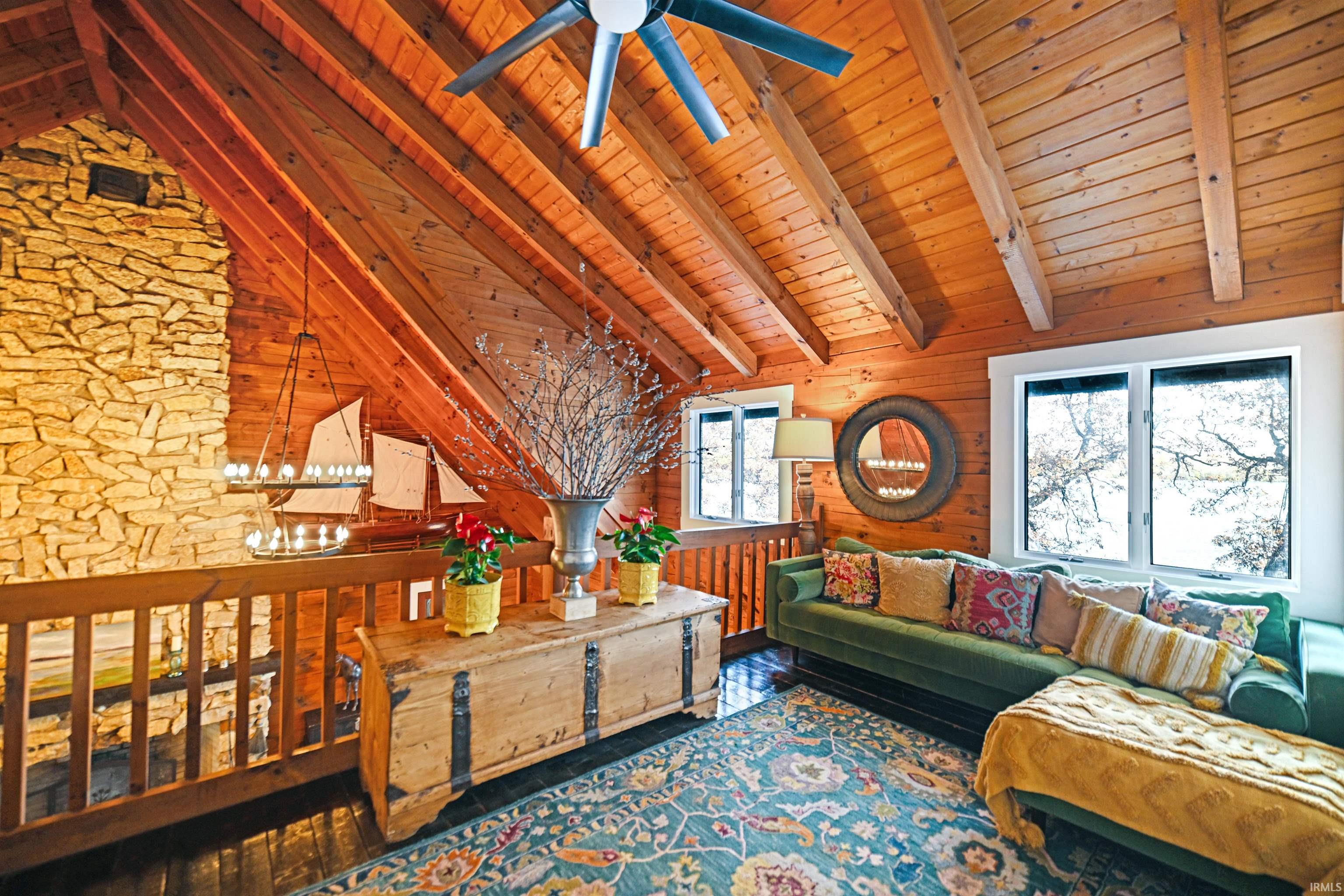 Living room with a wood ceiling with exposed beams, wood walls, hardwood / wood-style flooring, high vaulted ceiling, and a chandelier