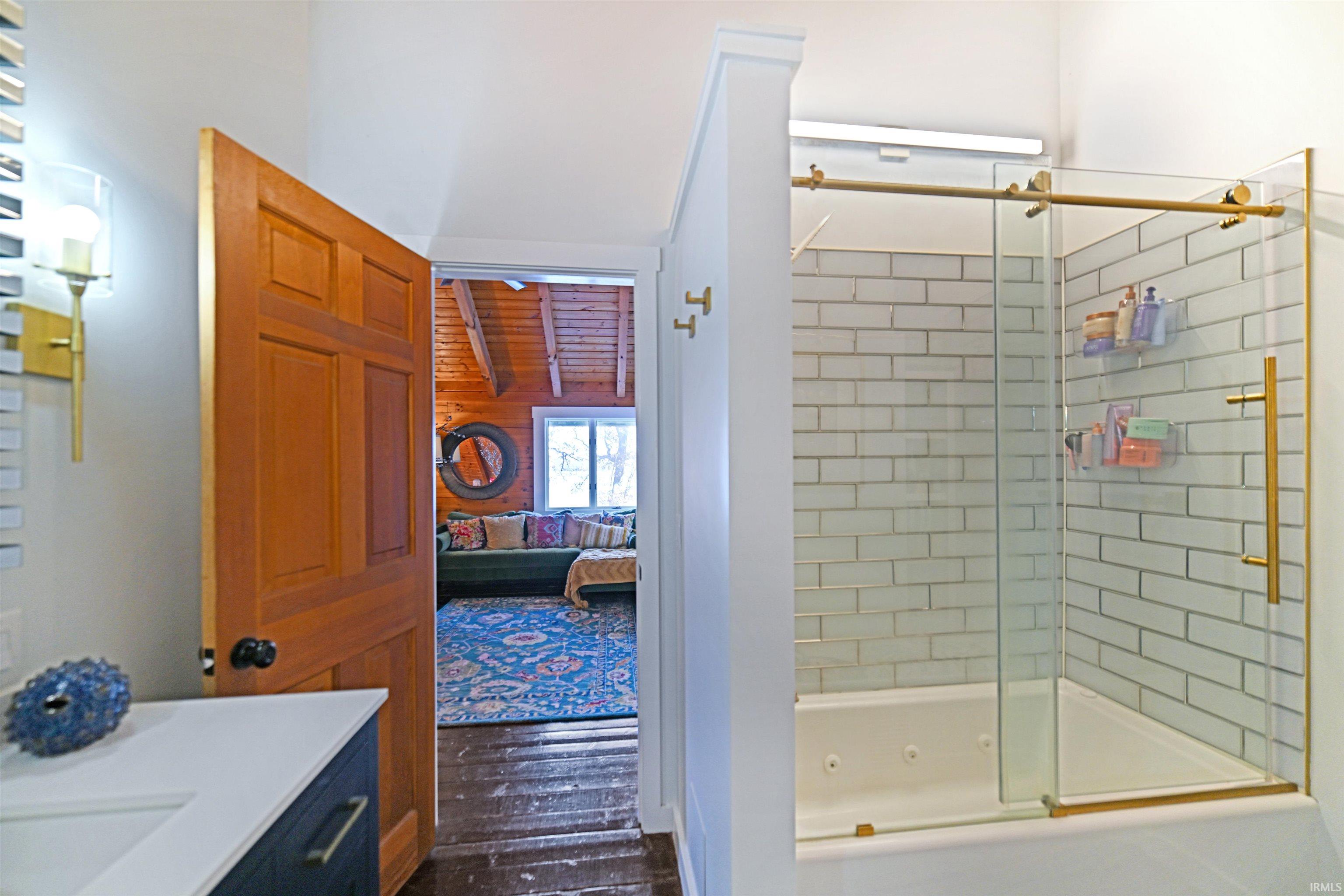 Ensuite bathroom featuring vanity, a combined bath / shower with jetted tub, and dark wood-style floors