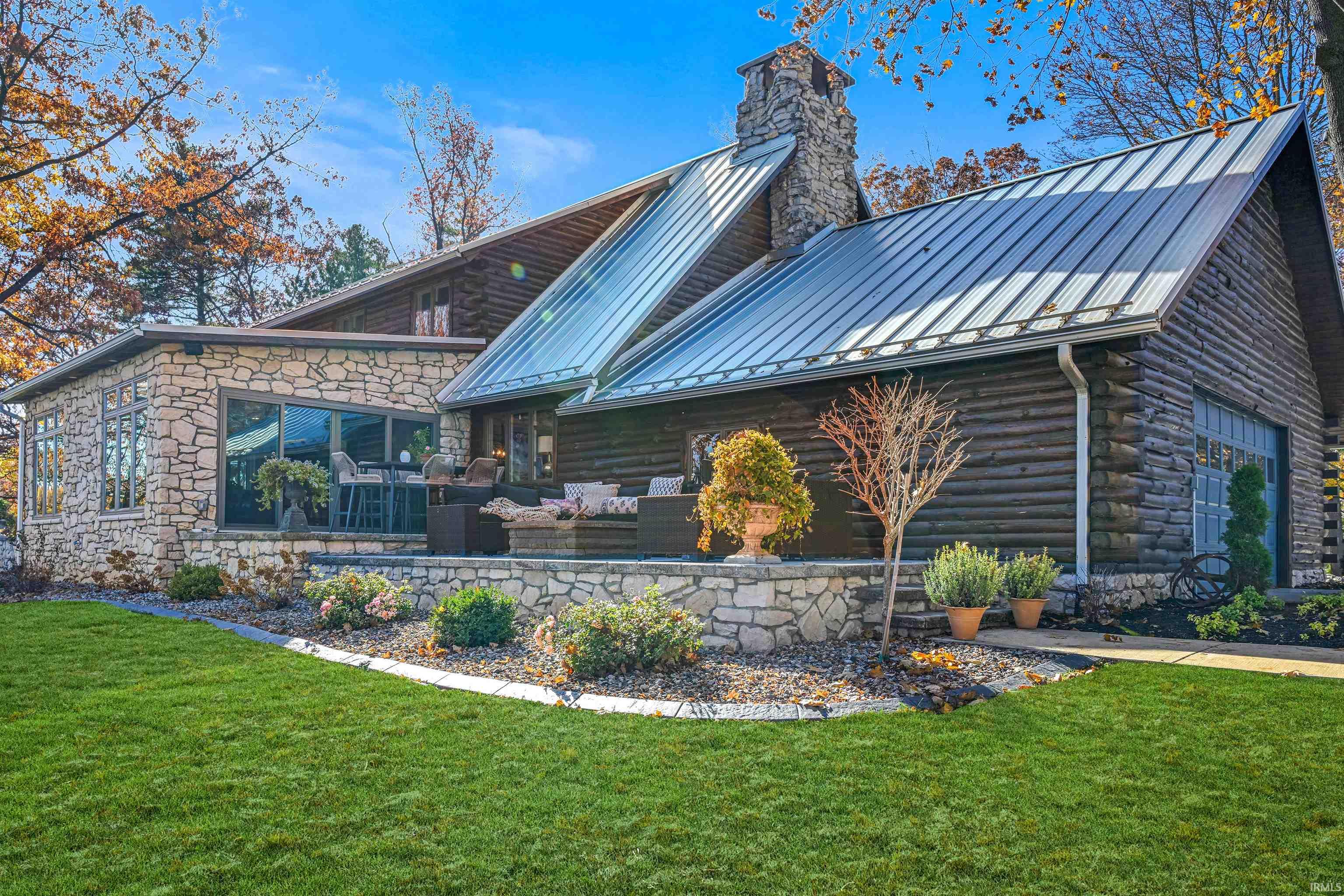 Rear view of house with a chimney, a lawn, and log siding