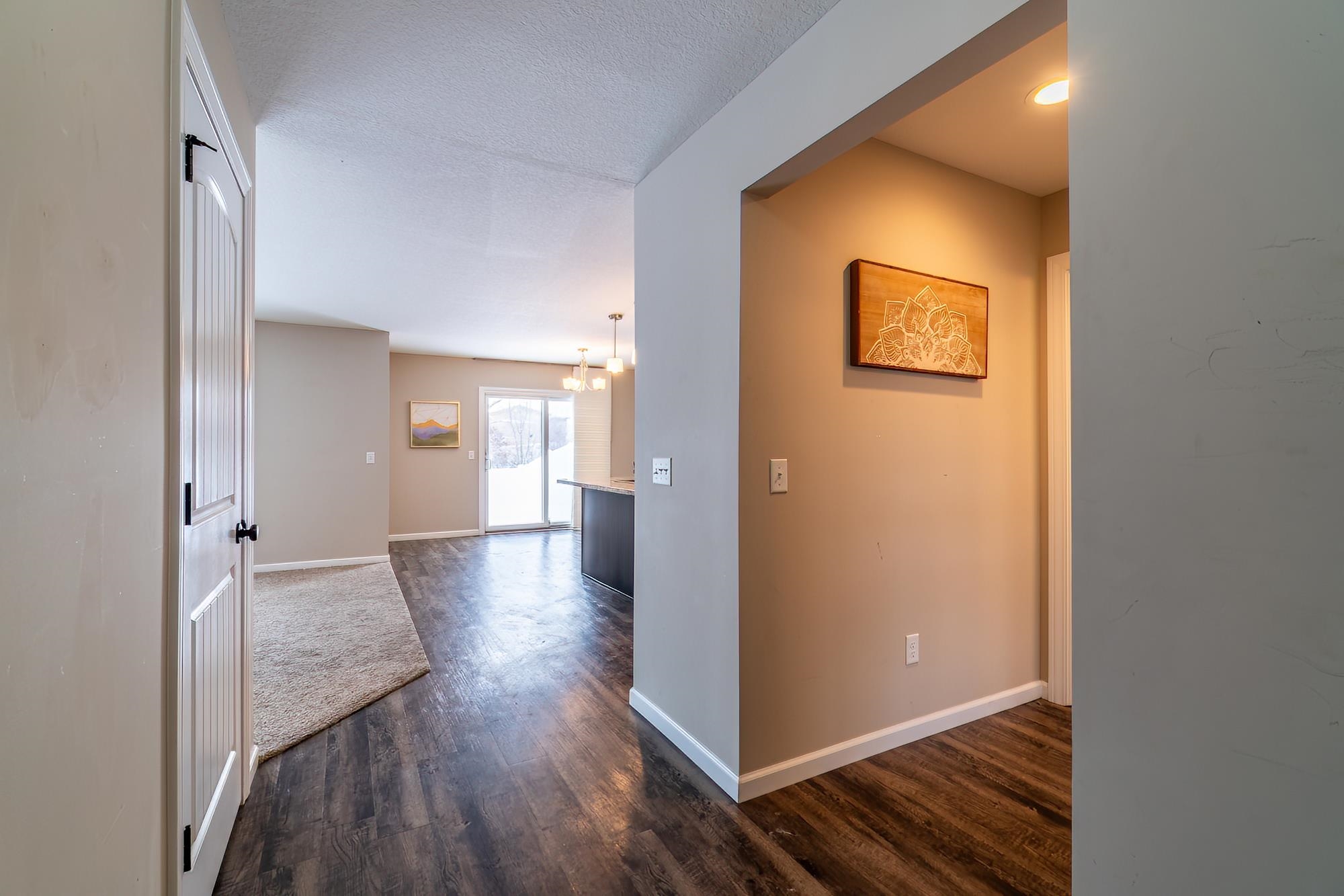 Hallway featuring a chandelier, dark wood-type flooring, and a textured ceiling