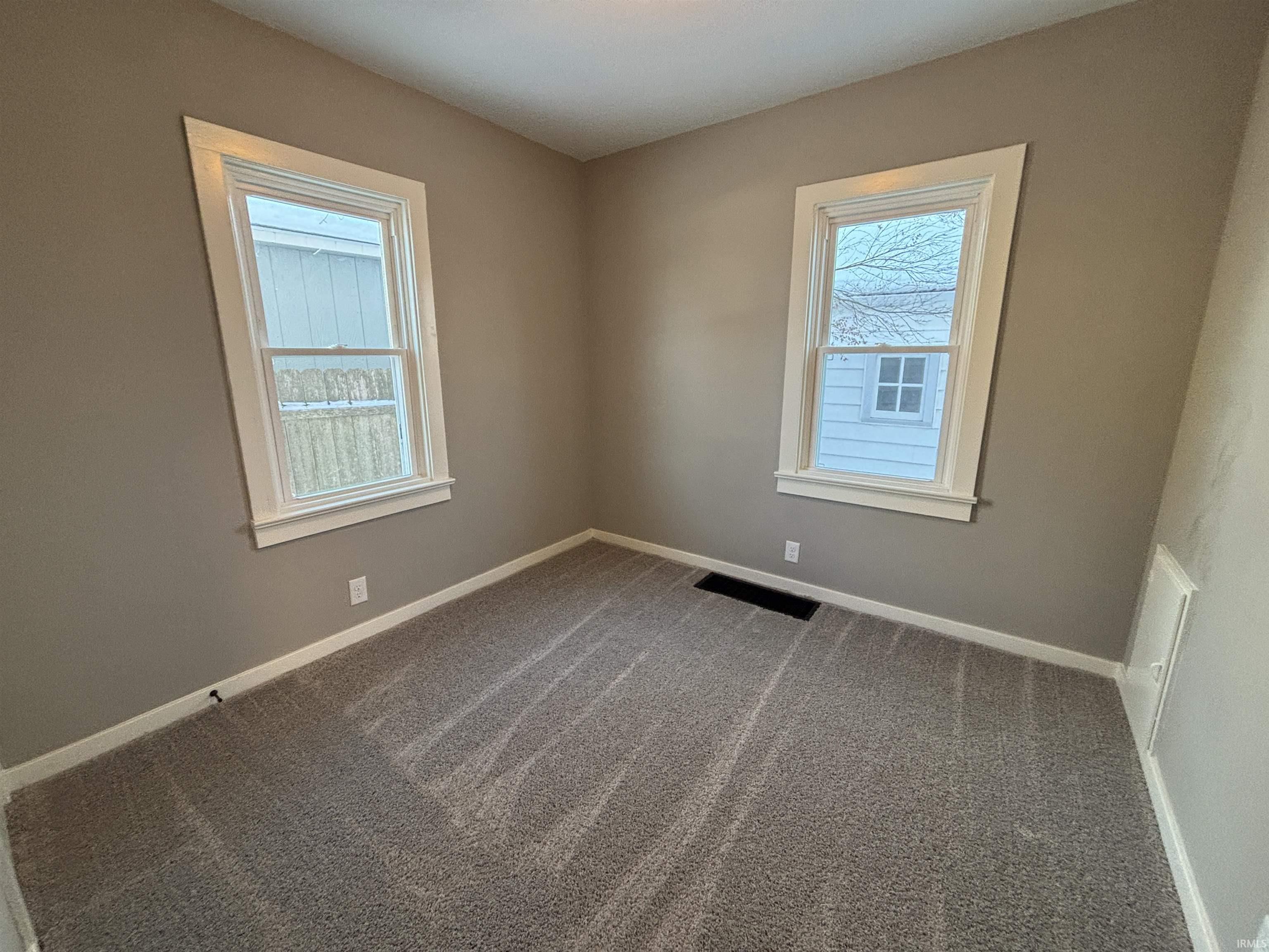 Carpeted spare room featuring healthy amount of natural light