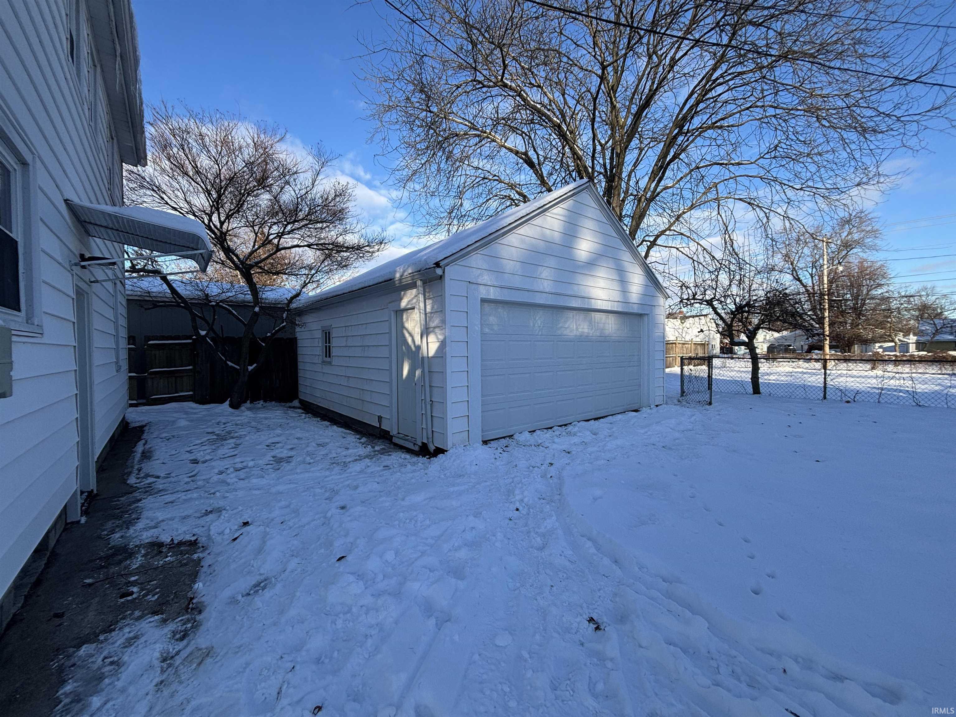 Snow covered garage with a detached garage
