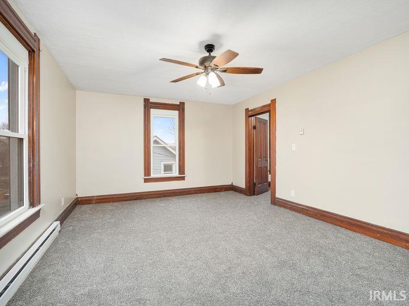 Unfurnished room with a baseboard heating unit, light carpet, and a ceiling fan