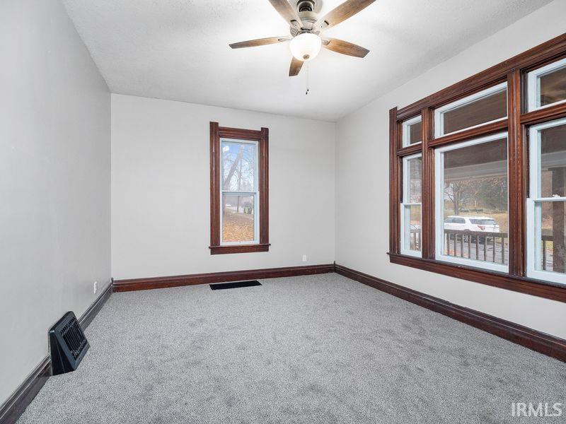 Carpeted empty room featuring baseboards and ceiling fan