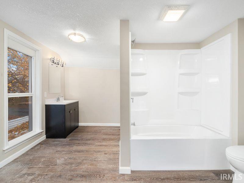 Full bath featuring vanity, a textured ceiling, light wood-style flooring, and shower / washtub combination