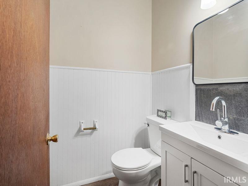 Half bathroom with a wainscoted wall and vanity