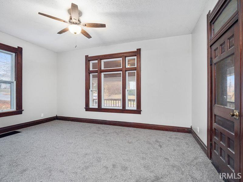 Spare room featuring healthy amount of natural light, carpet flooring, a textured ceiling, and ceiling fan