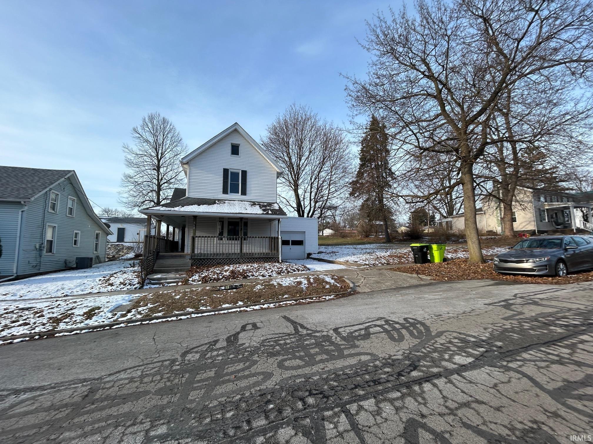 View of front facade with a porch, driveway, and a garage