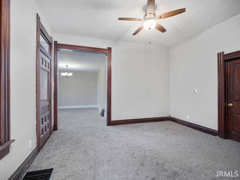 Spare room with light carpet, ceiling fan, a textured ceiling, and a chandelier