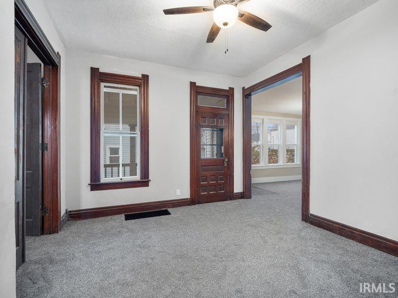 Empty room featuring carpet flooring, a textured ceiling, and ceiling fan