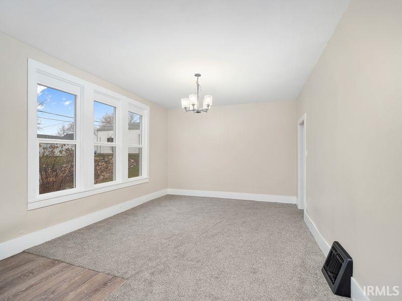 Spare room with a chandelier, light carpet, and light wood-type flooring
