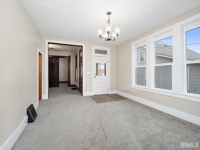 Unfurnished dining area with a chandelier and carpet flooring