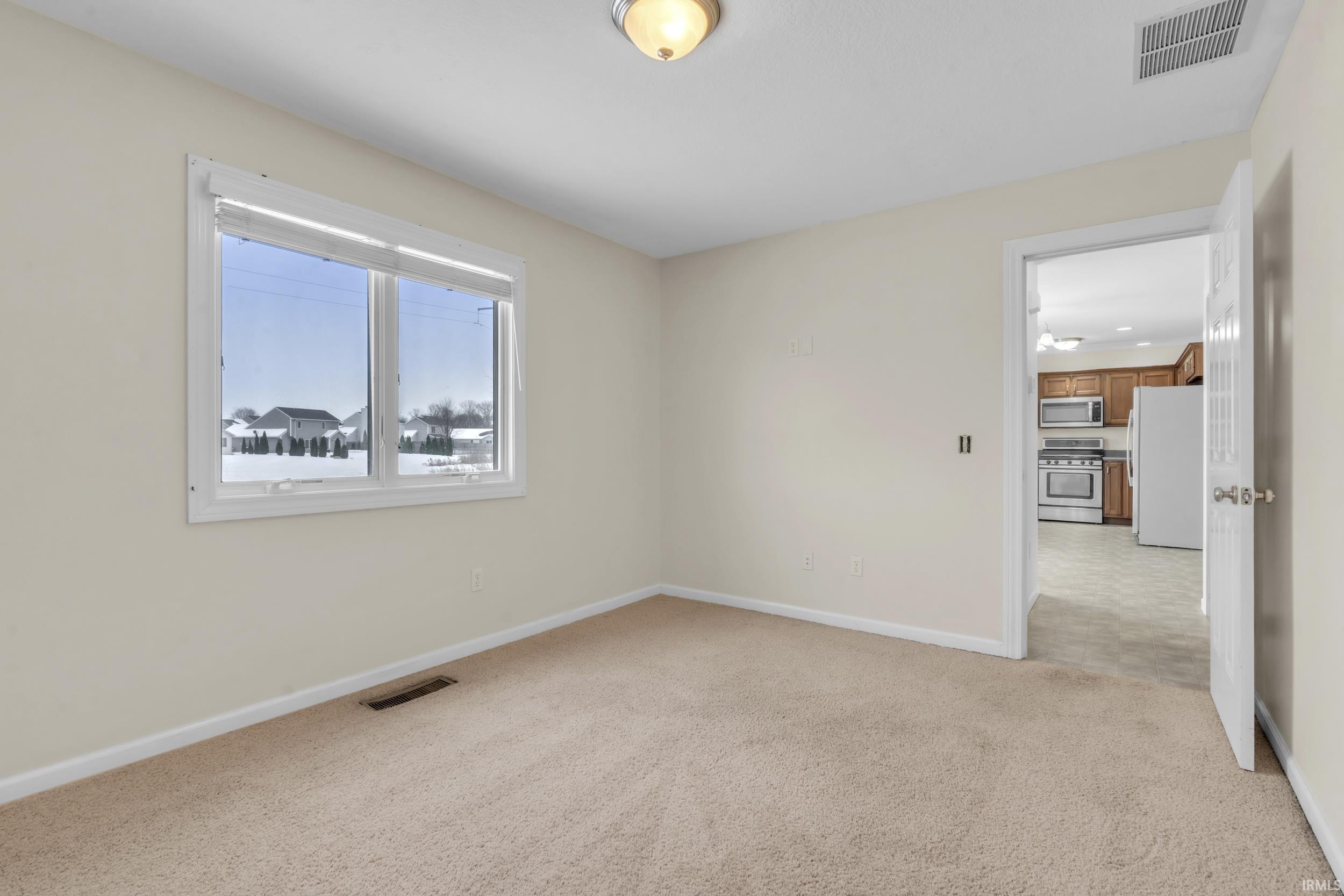 Empty room featuring light carpet and baseboards