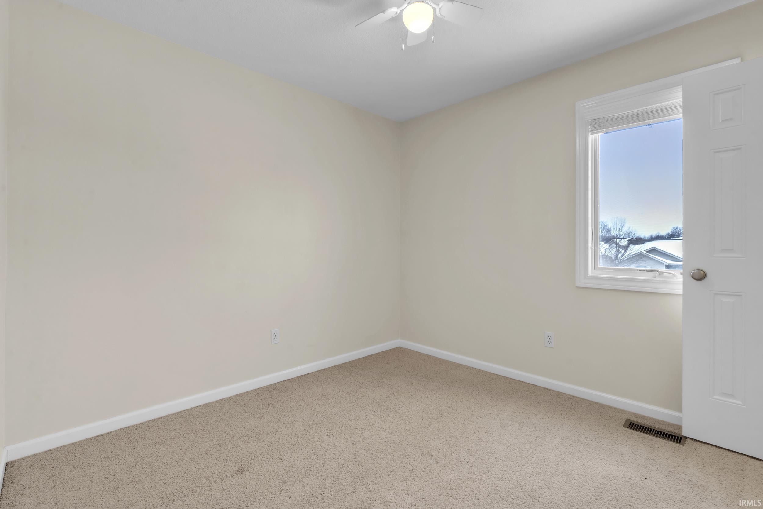 Carpeted spare room featuring baseboards and a ceiling fan