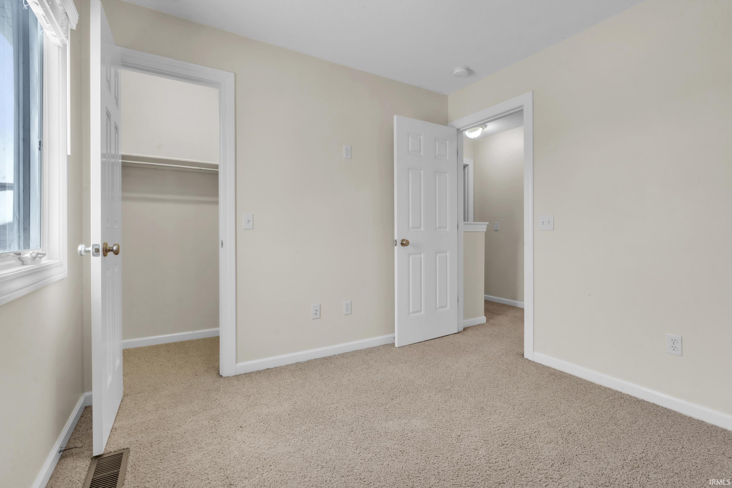 Unfurnished bedroom with light carpet and a spacious closet
