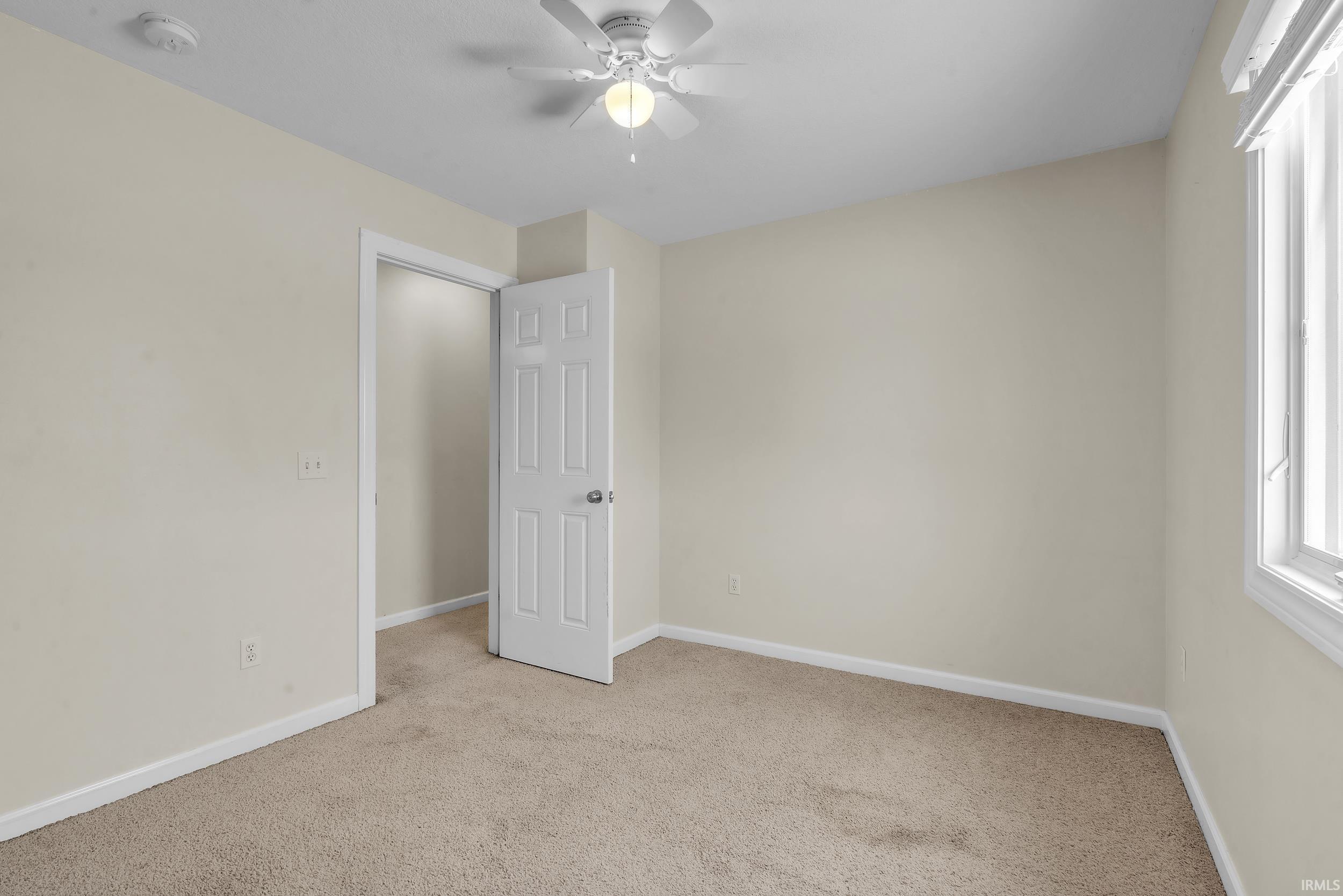 Unfurnished bedroom featuring light carpet and ceiling fan