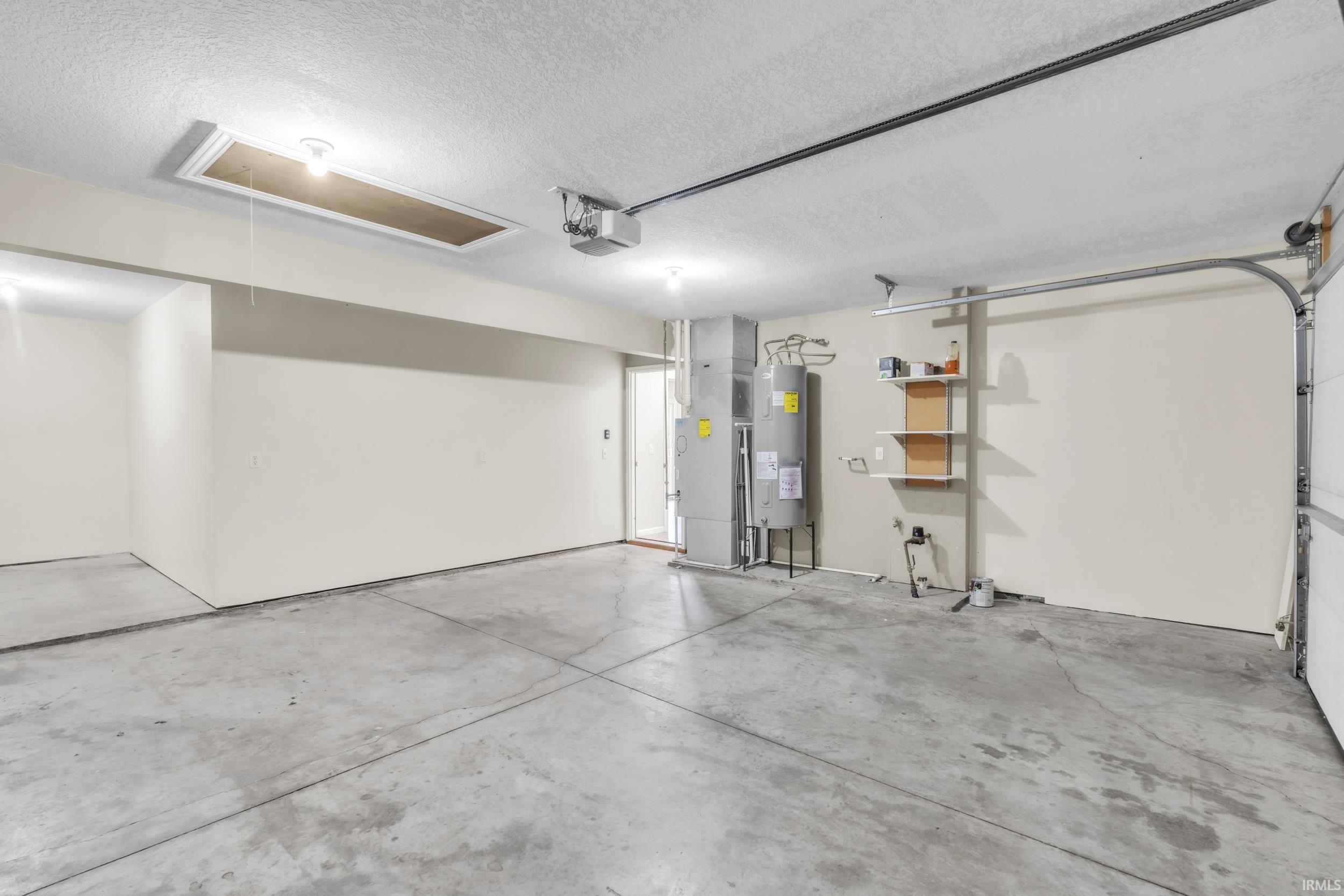 Garage with heating unit, electric water heater, and a garage door opener