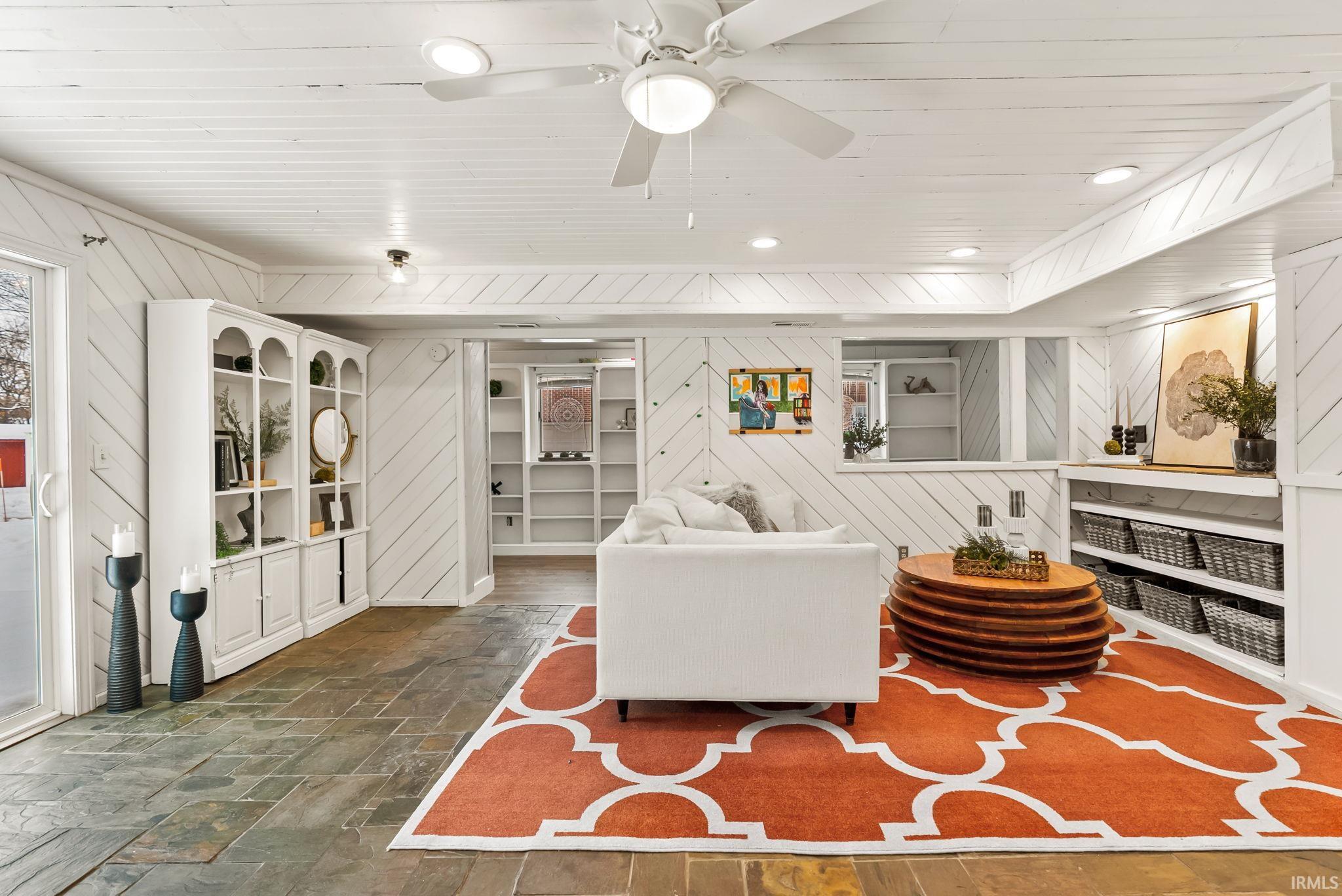 Living room featuring wooden walls, wooden ceiling, stone tile flooring, recessed lighting, and a ceiling fan