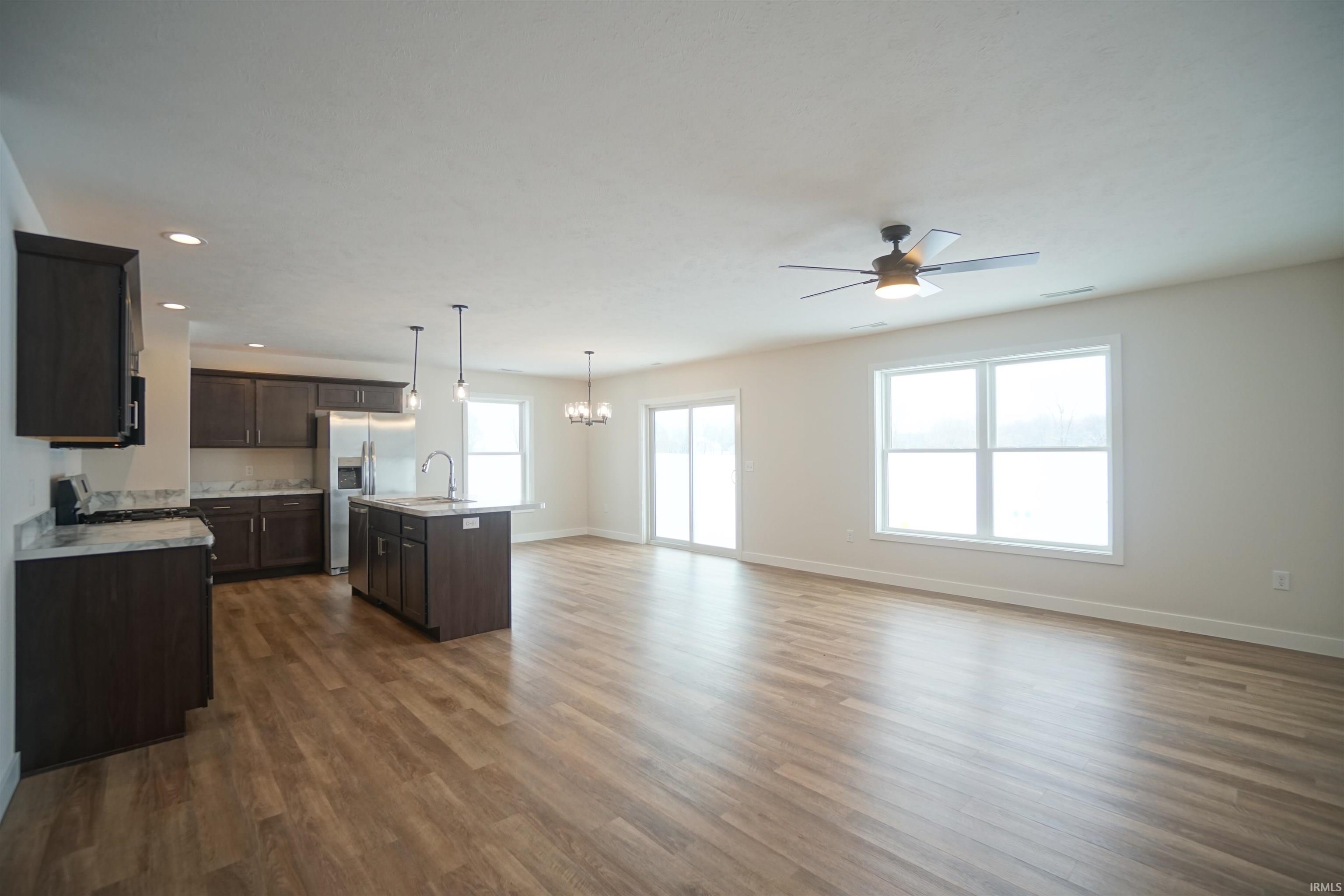 Kitchen with a kitchen island with sink, open floor plan, decorative light fixtures, recessed lighting, and a chandelier