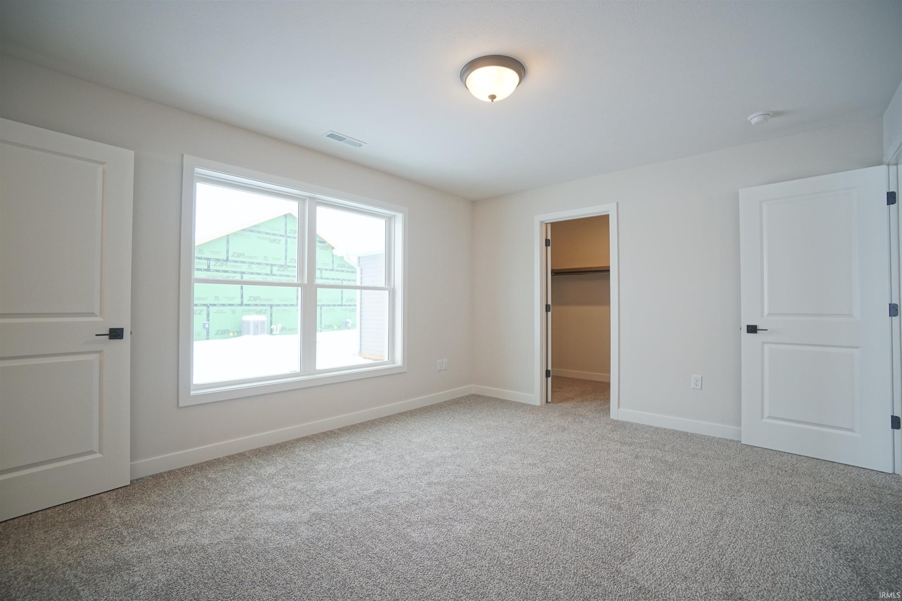 Unfurnished bedroom with a spacious closet and light carpet
