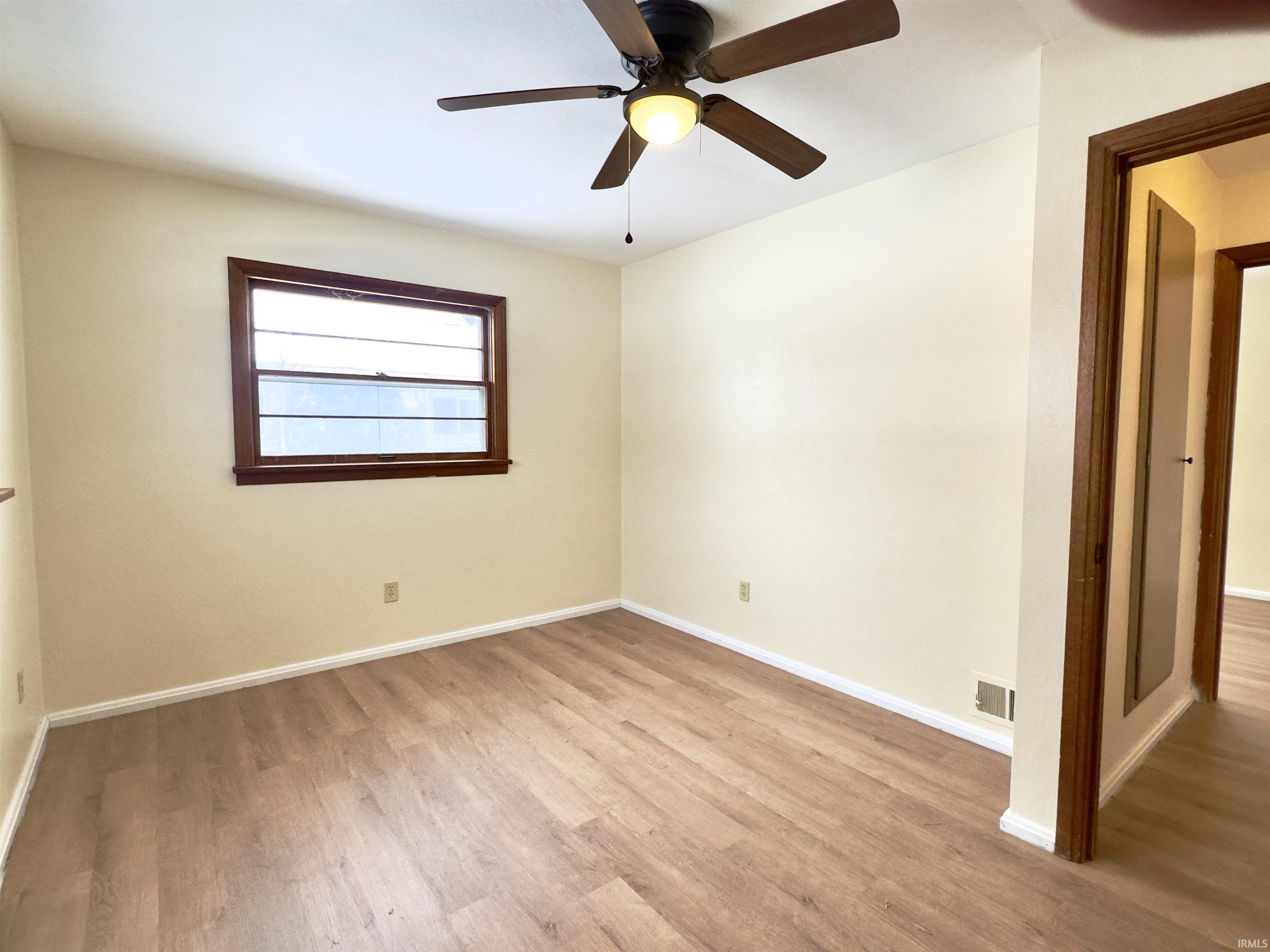 Empty room with light wood-style floors and ceiling fan