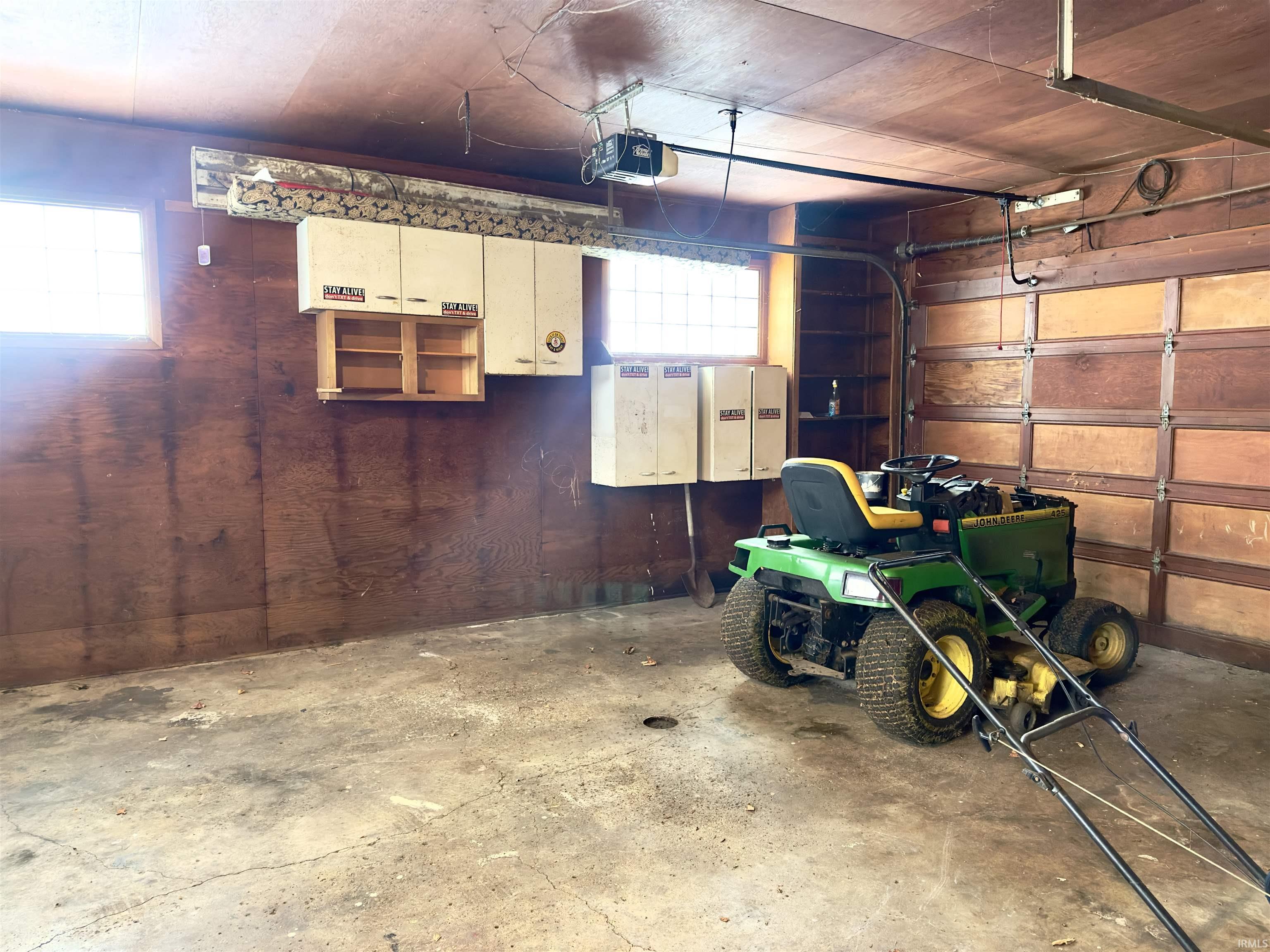 Garage featuring wooden walls, wood ceiling, and a garage door opener