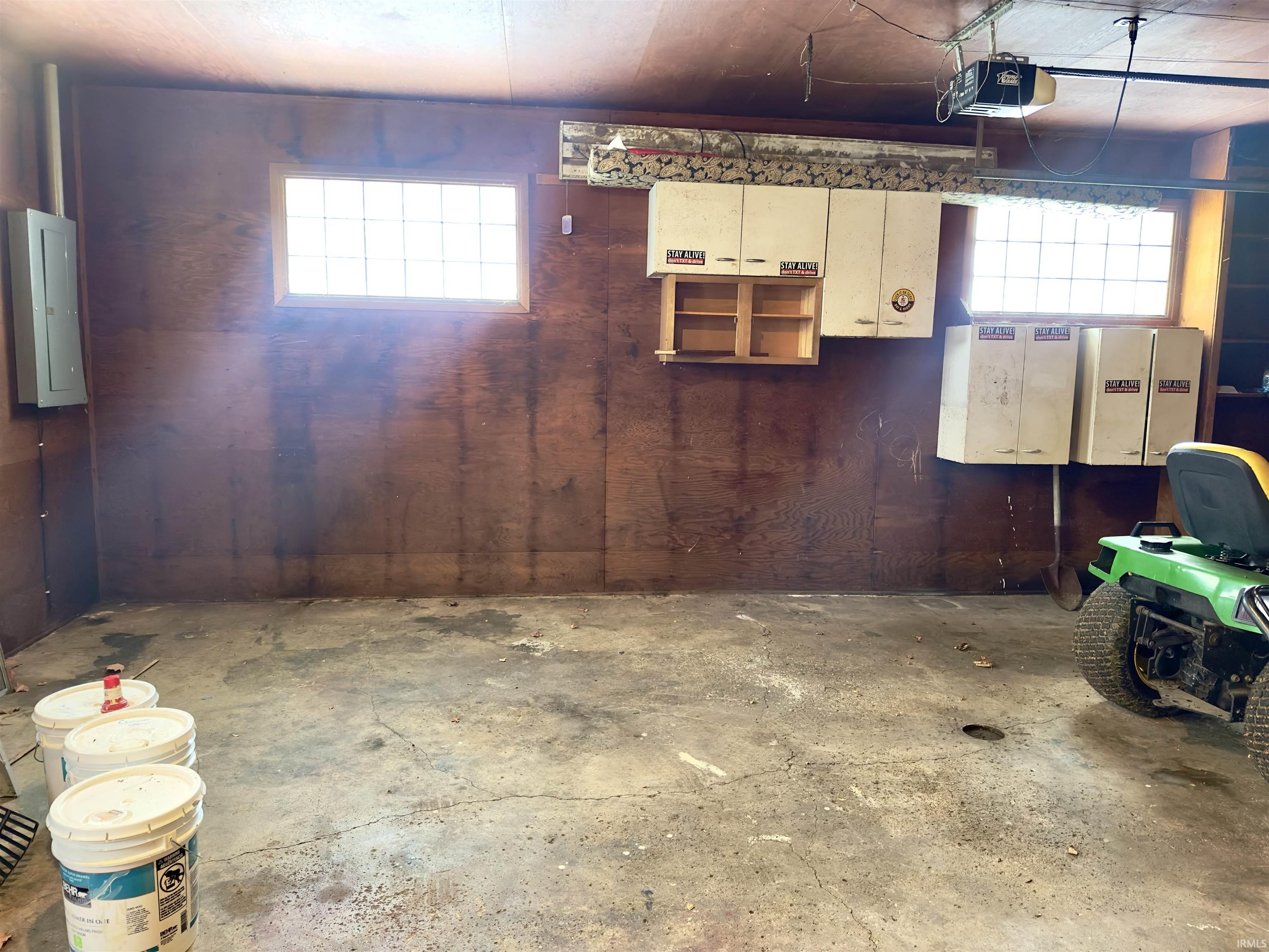 Garage featuring electric panel, wood walls, and a garage door opener