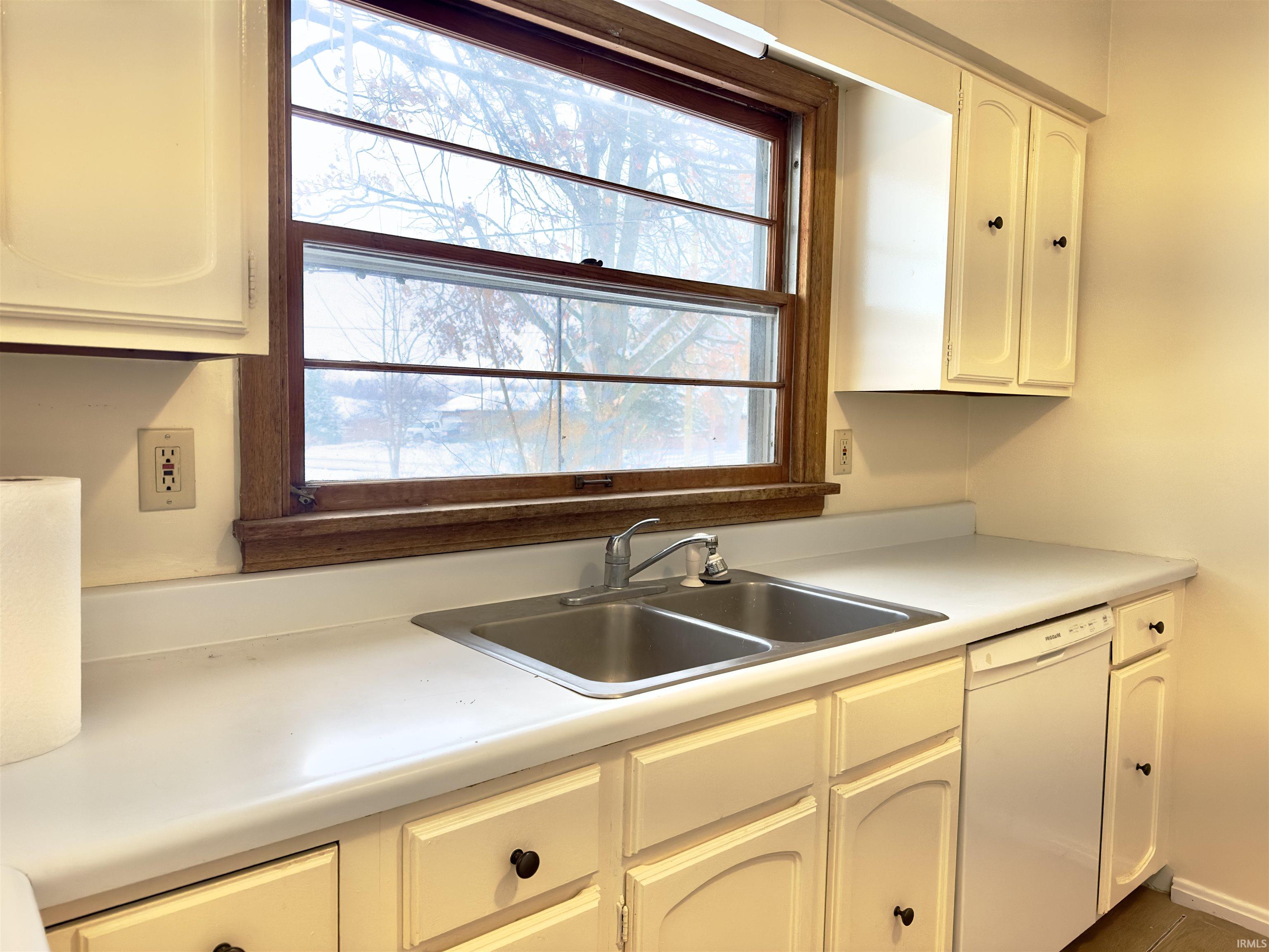 Kitchen featuring dishwasher, healthy amount of natural light, light countertops, and white cabinets