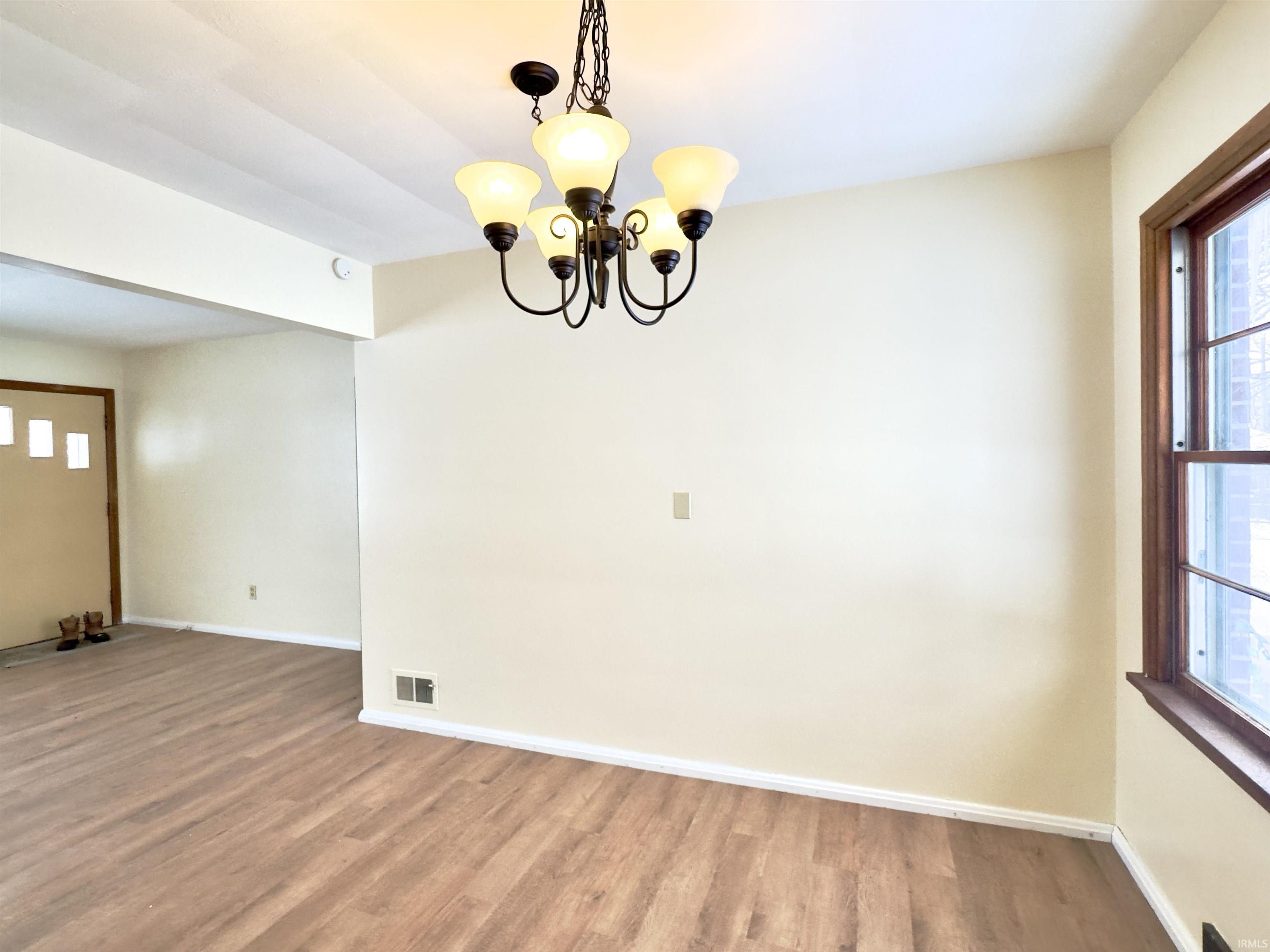 Unfurnished dining area featuring a chandelier and wood finished floors