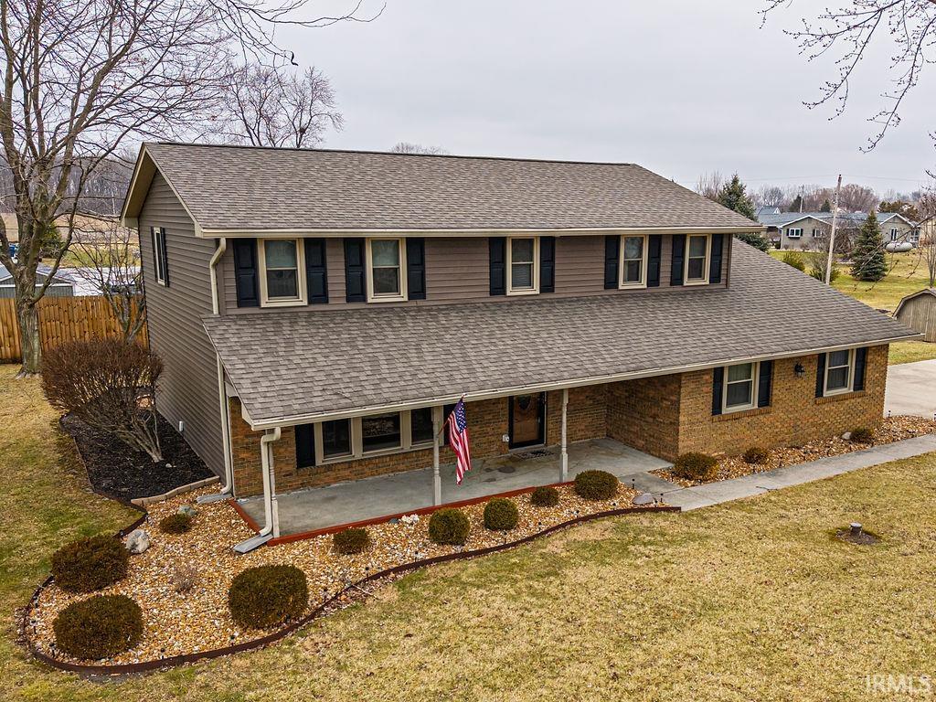 View of front of property with a shingled roof and brick siding