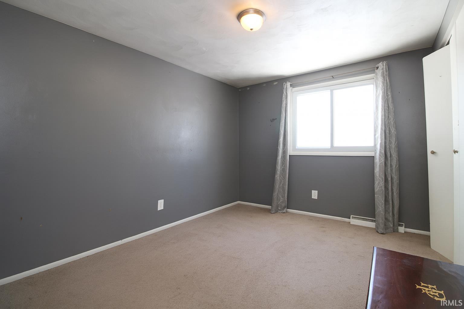 Spare room with baseboards and light carpet