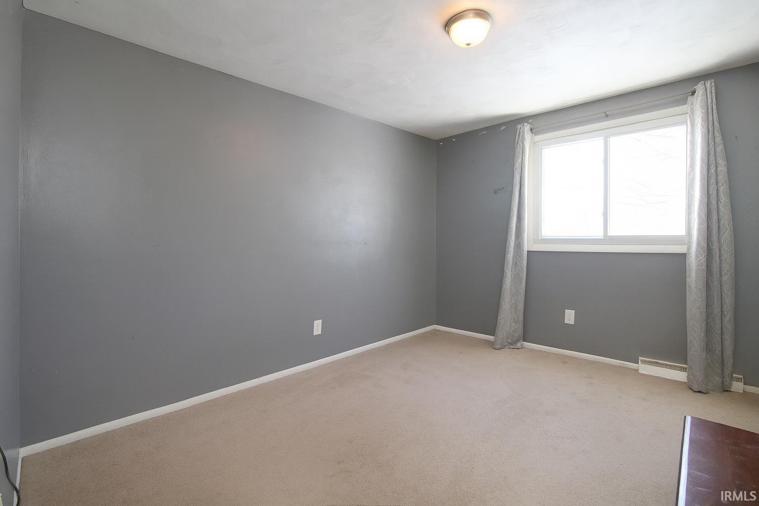 Unfurnished room with baseboards and light carpet