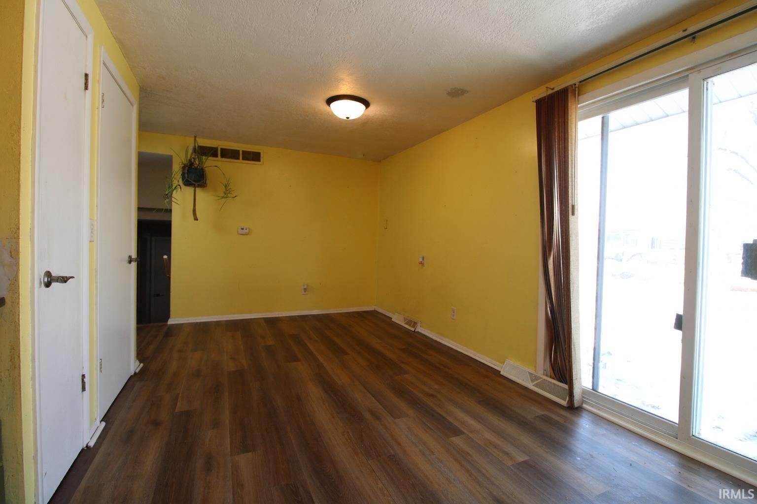Empty room featuring dark wood-type flooring and a textured ceiling