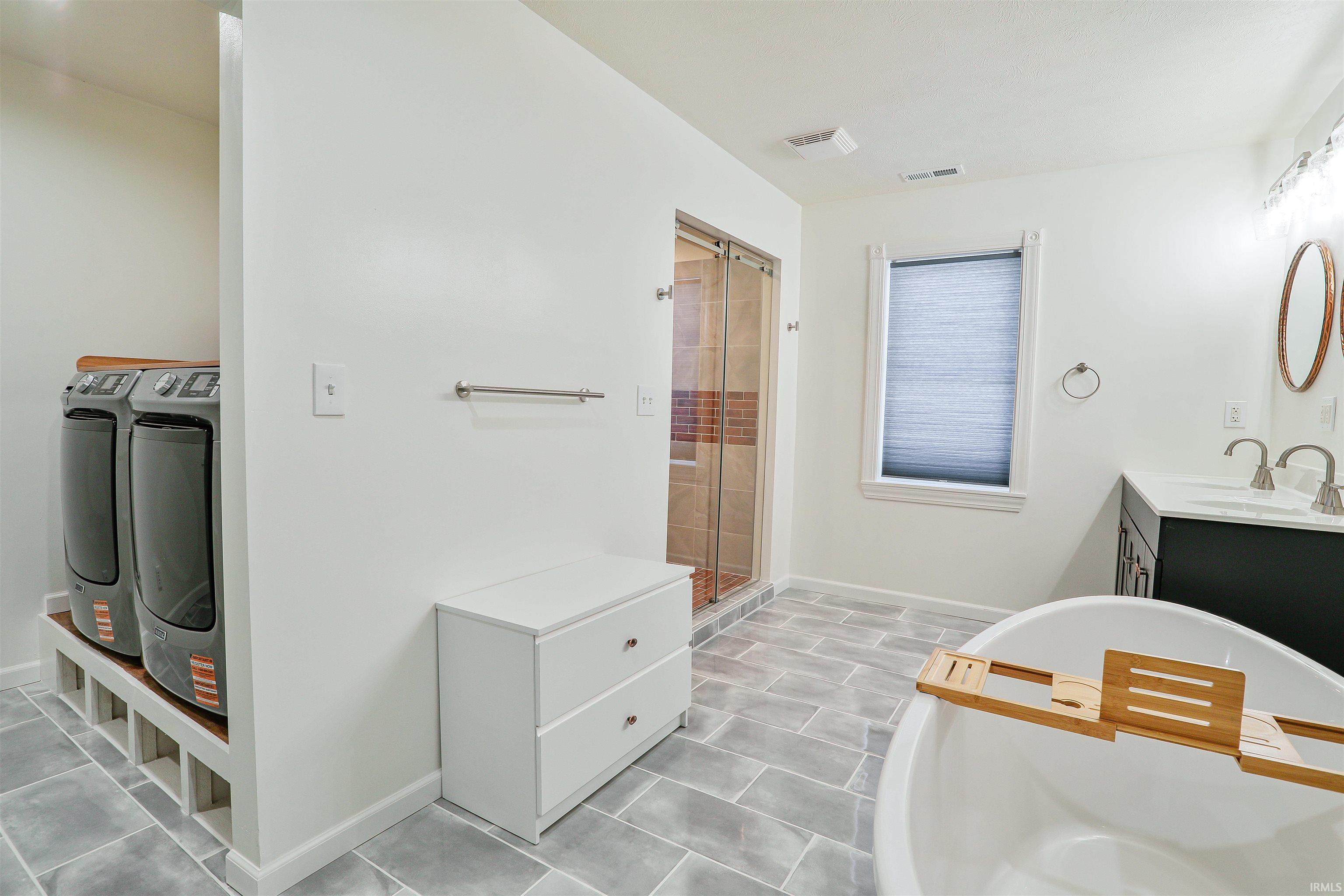 Bathroom with vanity, a freestanding tub, and a stall shower