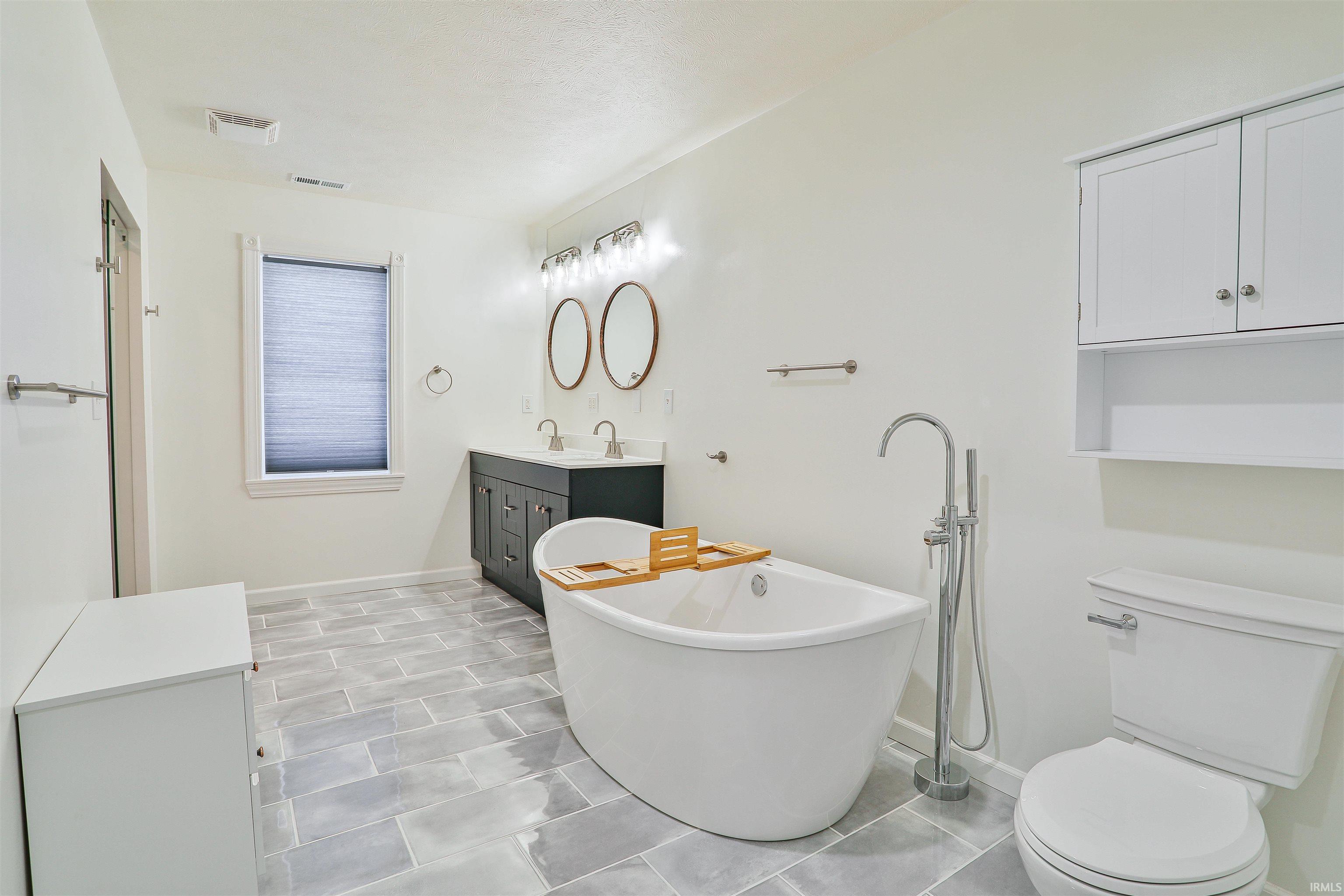 Full bathroom with vanity and a soaking tub