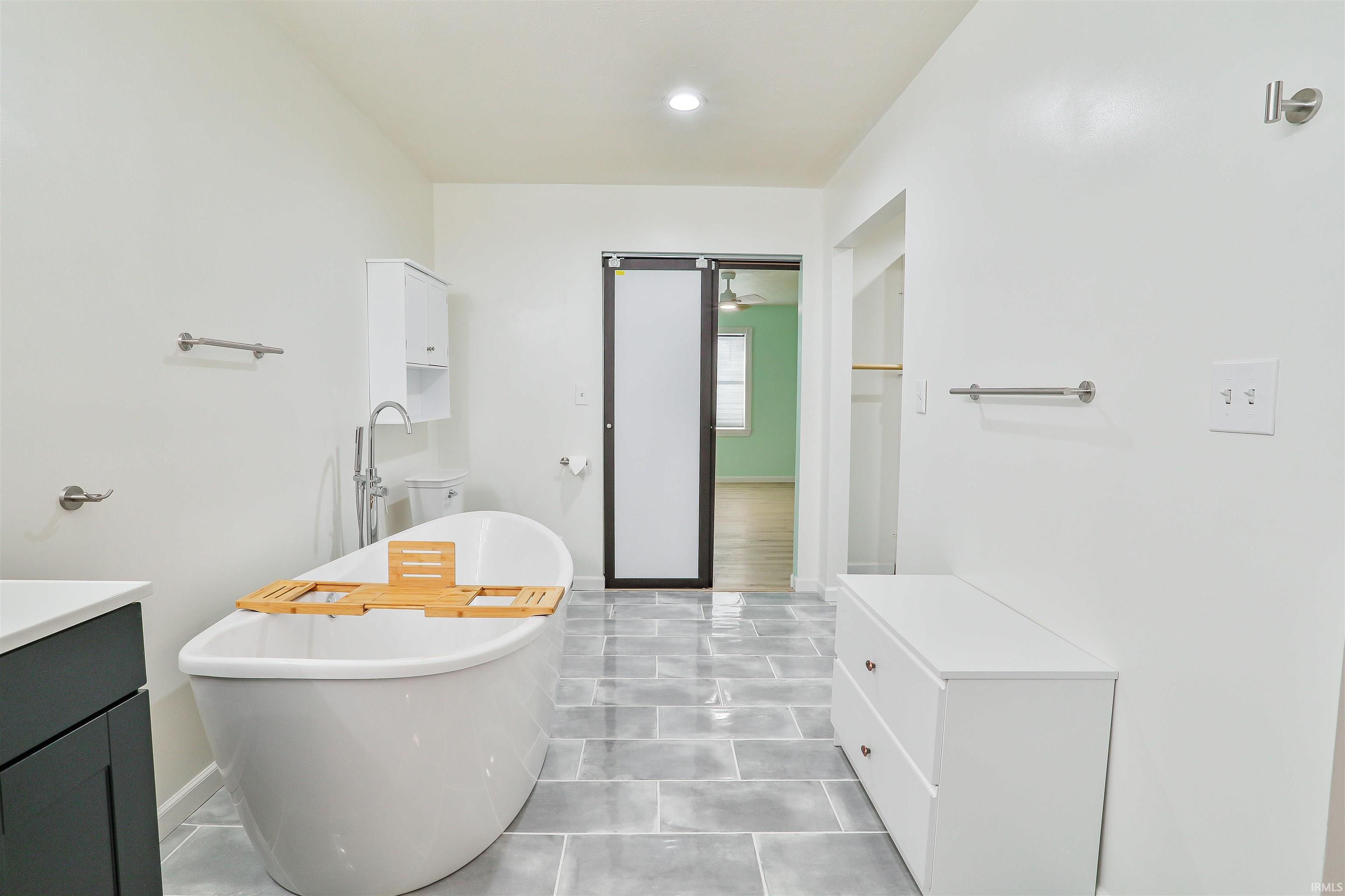 Full bathroom featuring a soaking tub, vanity, and recessed lighting