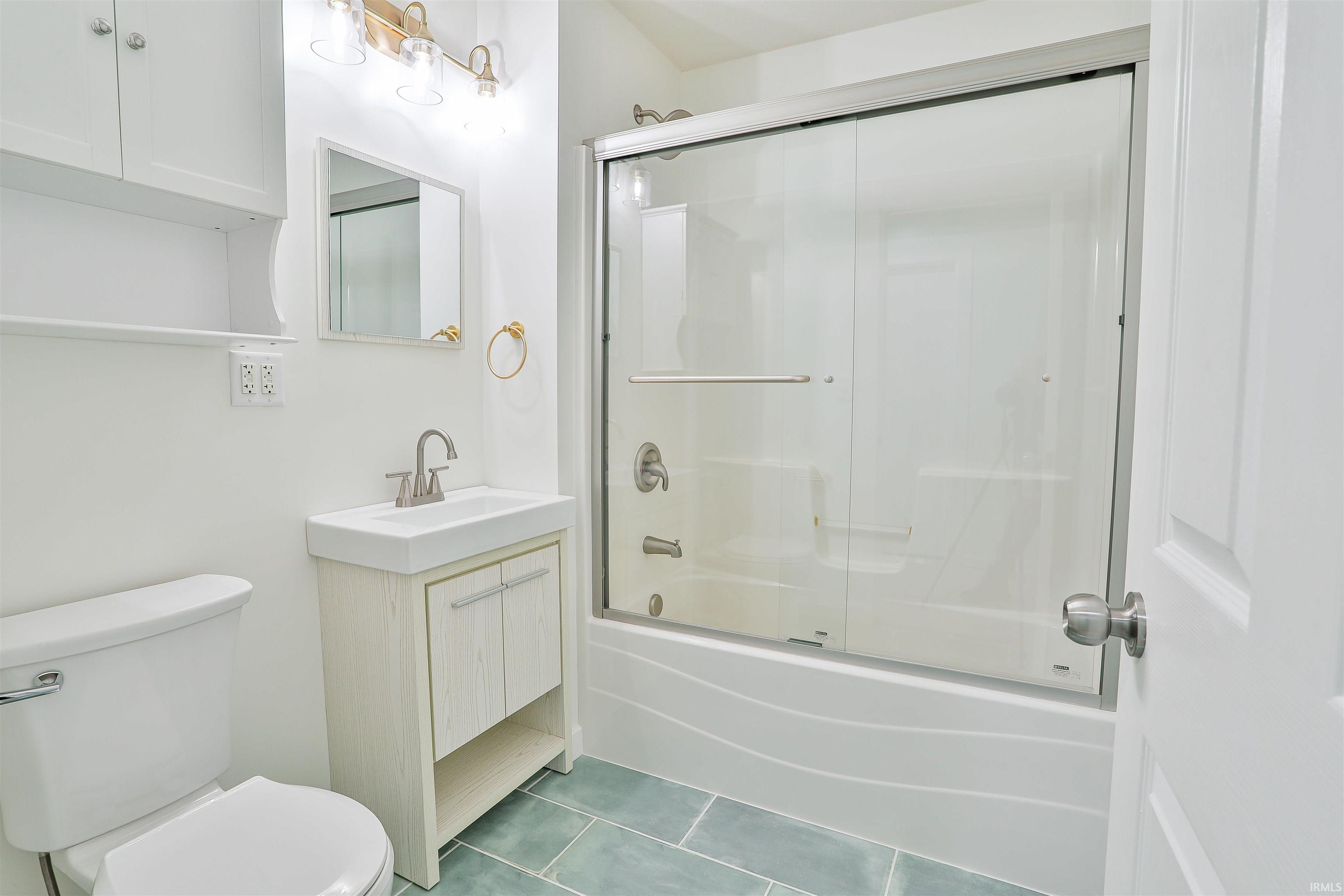 Full bath with combined bath / shower with glass door, tile patterned floors, and vanity